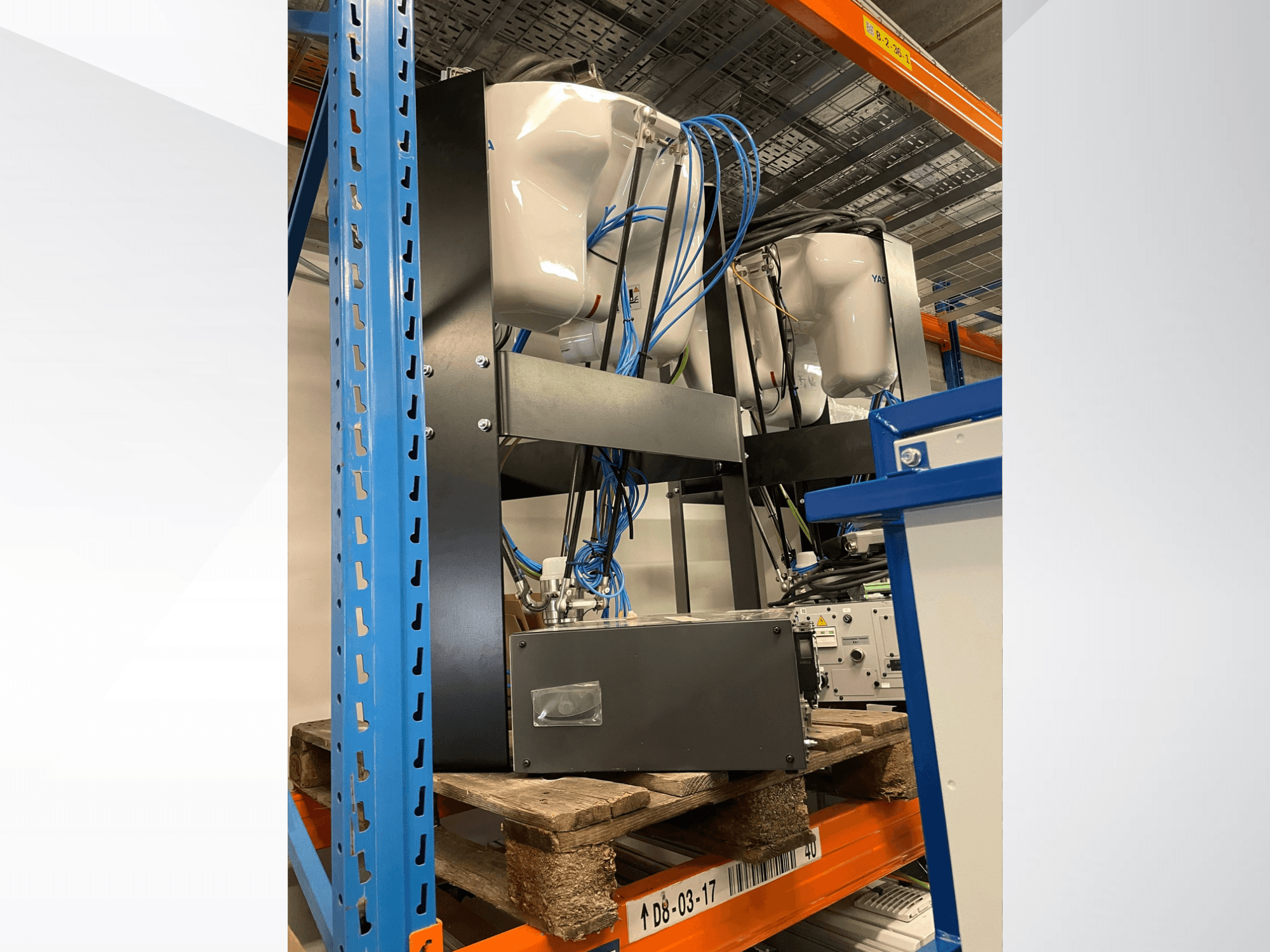 Роботизированный манипулятор Yaskawa Motoman MPP3H, изображенный в виде сбоку, с видимыми проводами и компонентами на стеллаже для хранения.