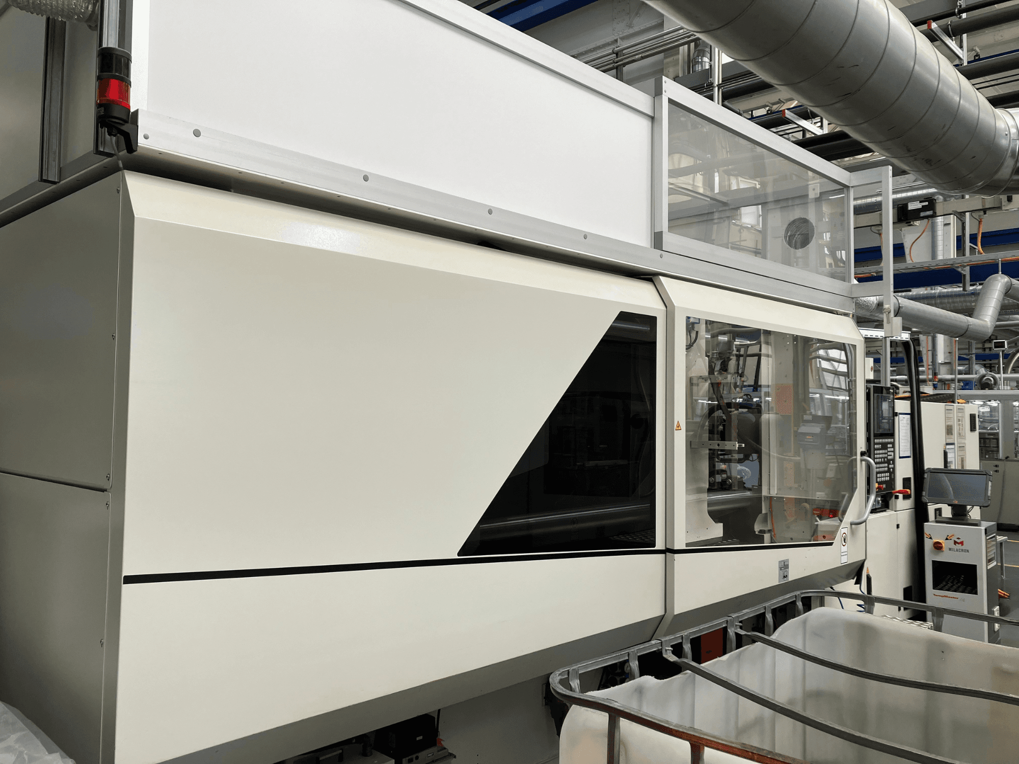 Вид спереди промышленного станка с элегантным белым дизайном, панелью дисплея и стеклянной секцией для обзора компонентов.