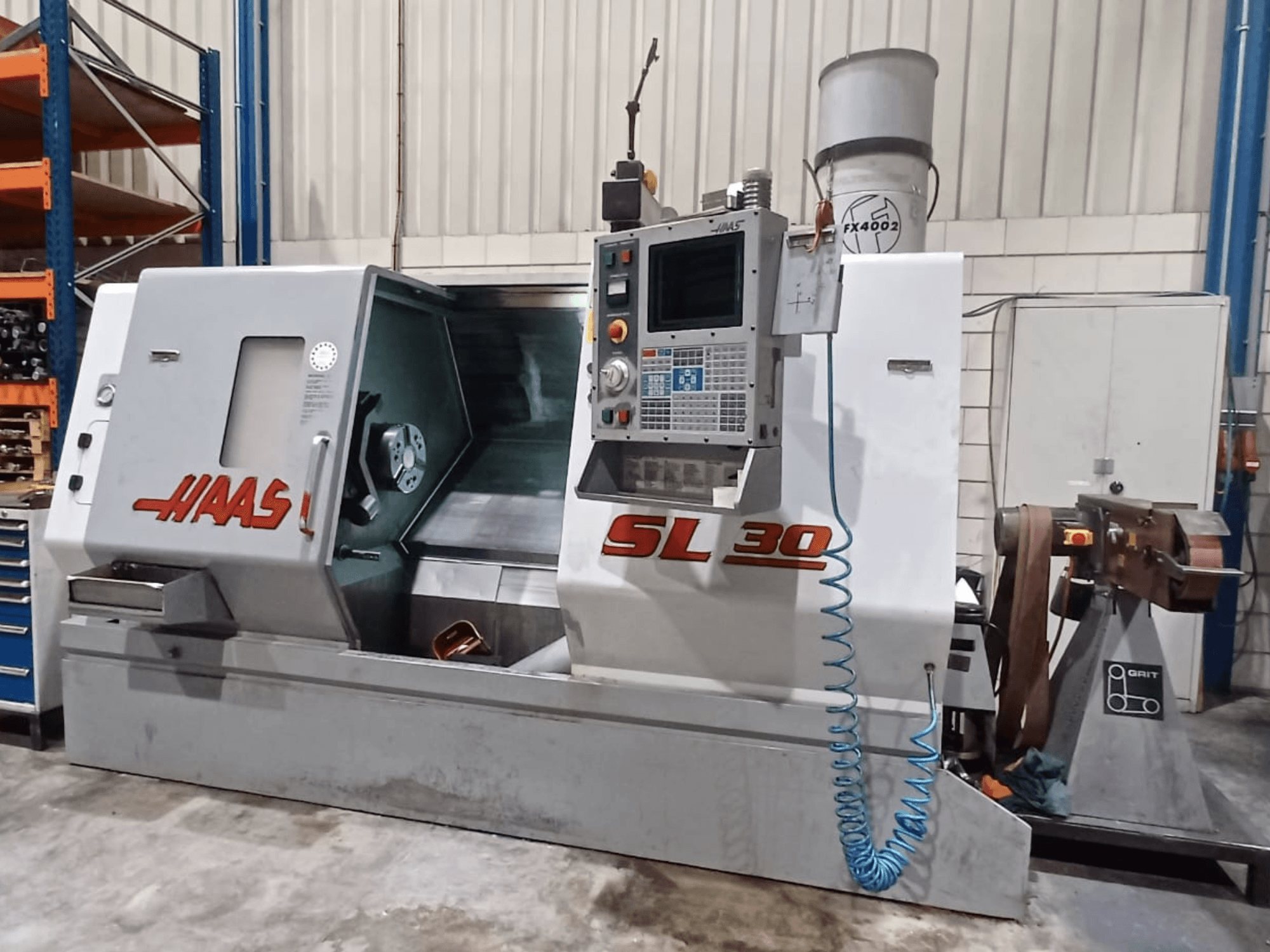 Токарный станок с ЧПУ Haas SL 30 с видом сбоку, демонстрирующий панель управления, зону обработки и систему охлаждения, встроенную в металлоконструкцию.