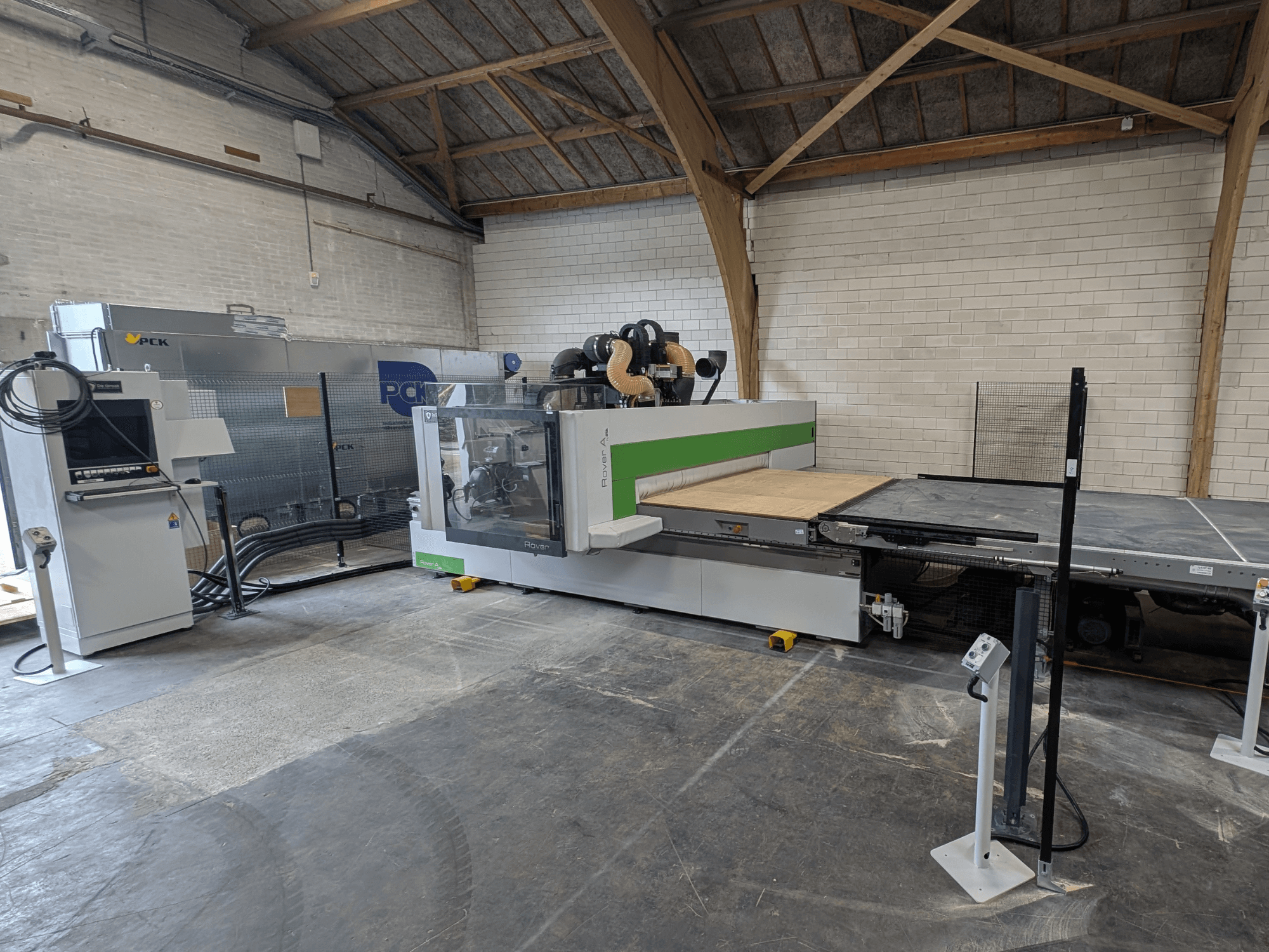 Обрабатывающий центр с ЧПУ PCK, вид спереди, имеет большую режущую станину, панель управления, систему пылеудаления и прочную конструкцию.