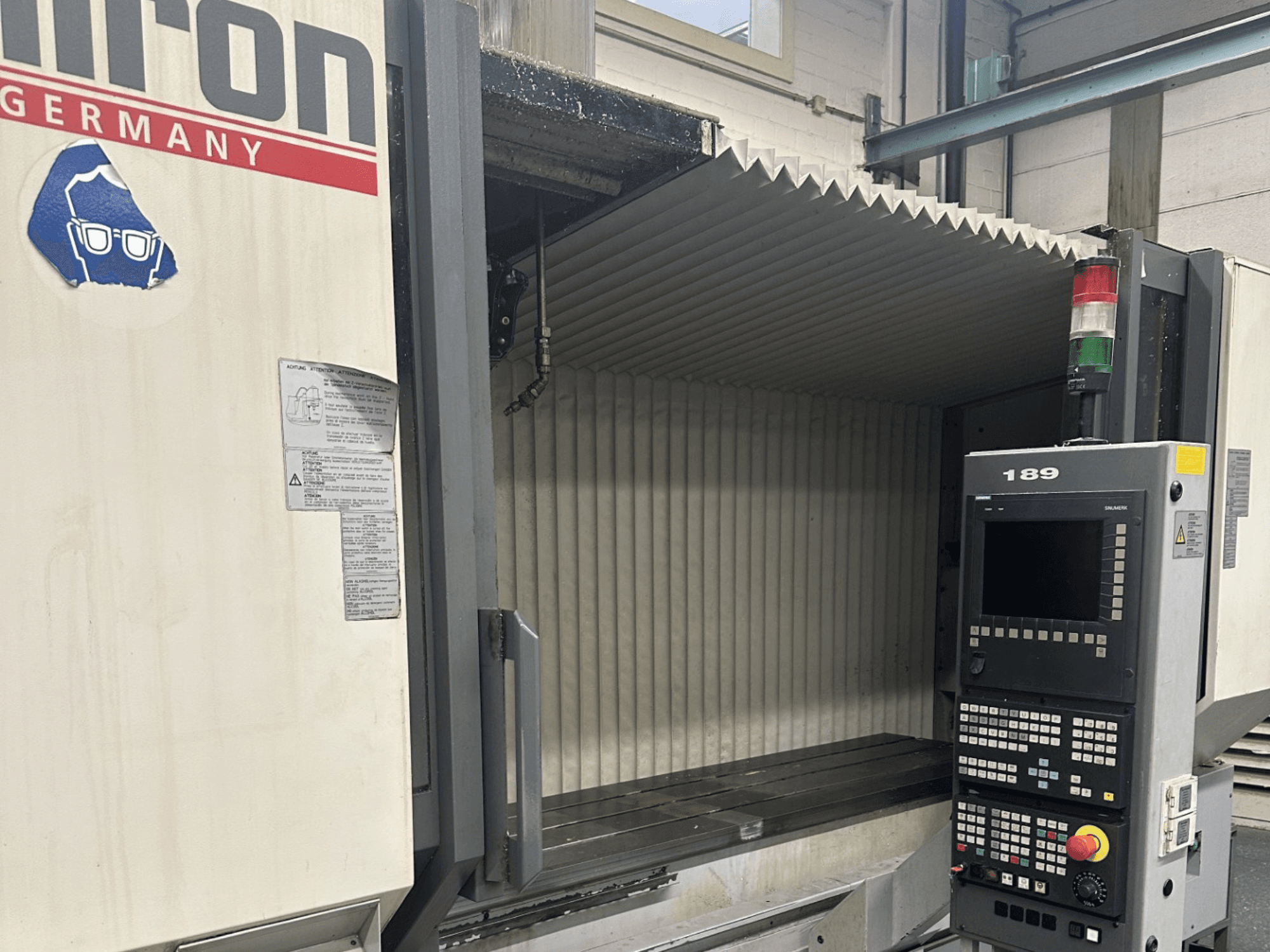 Alt text: Вид спереди на станок с ЧПУ Hermle с панелью управления с кнопками и дисплеем, с открытой рабочей зоной.