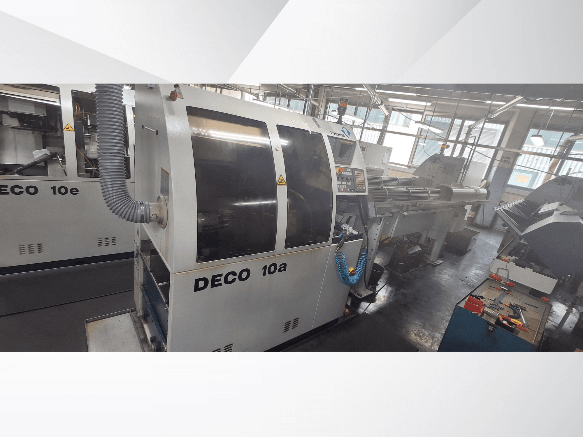 Станок с ЧПУ DECO 10a в мастерской, вид спереди, панель управления и выхлопная система. Отличается прочной конструкцией и точными инструментами.