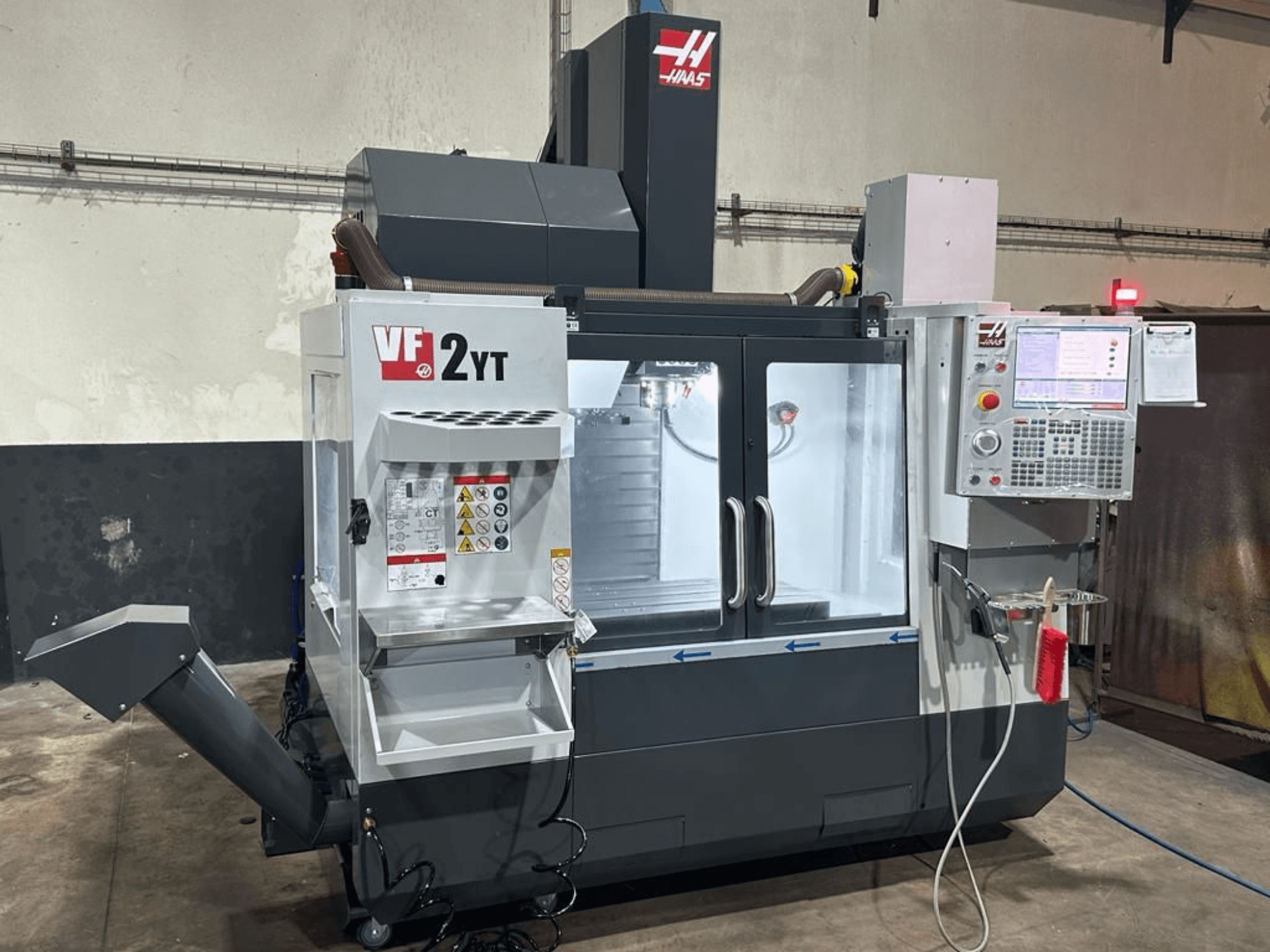 Вертикальный обрабатывающий центр HAAS VF-2YT-EU в виде спереди, на котором видны панель управления и отсек для хранения инструментов.