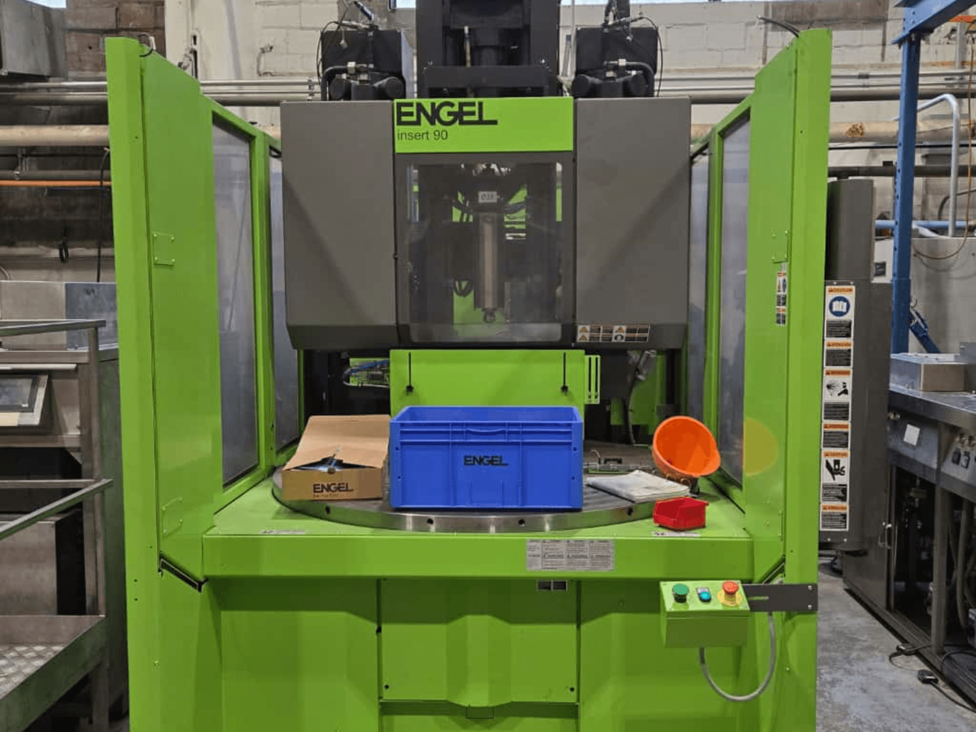 Зеленая машина для литья под давлением ENGEL Insert 90 с видом спереди, с синим контейнером и панелью управления с кнопками.