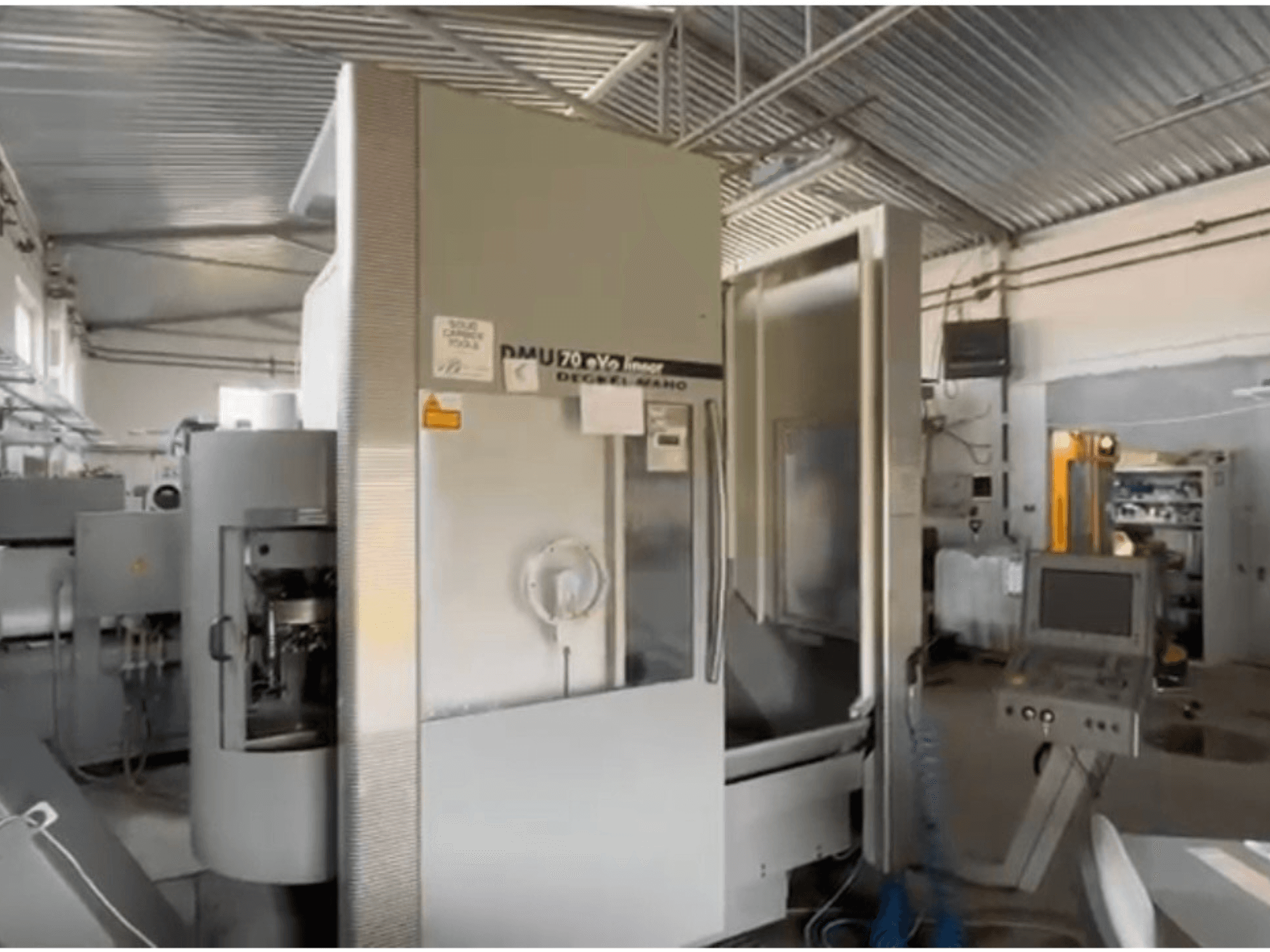 Линейный станок с ЧПУ DMU 70 eVo в мастерской, вид спереди, с панелью управления и современным дизайном.