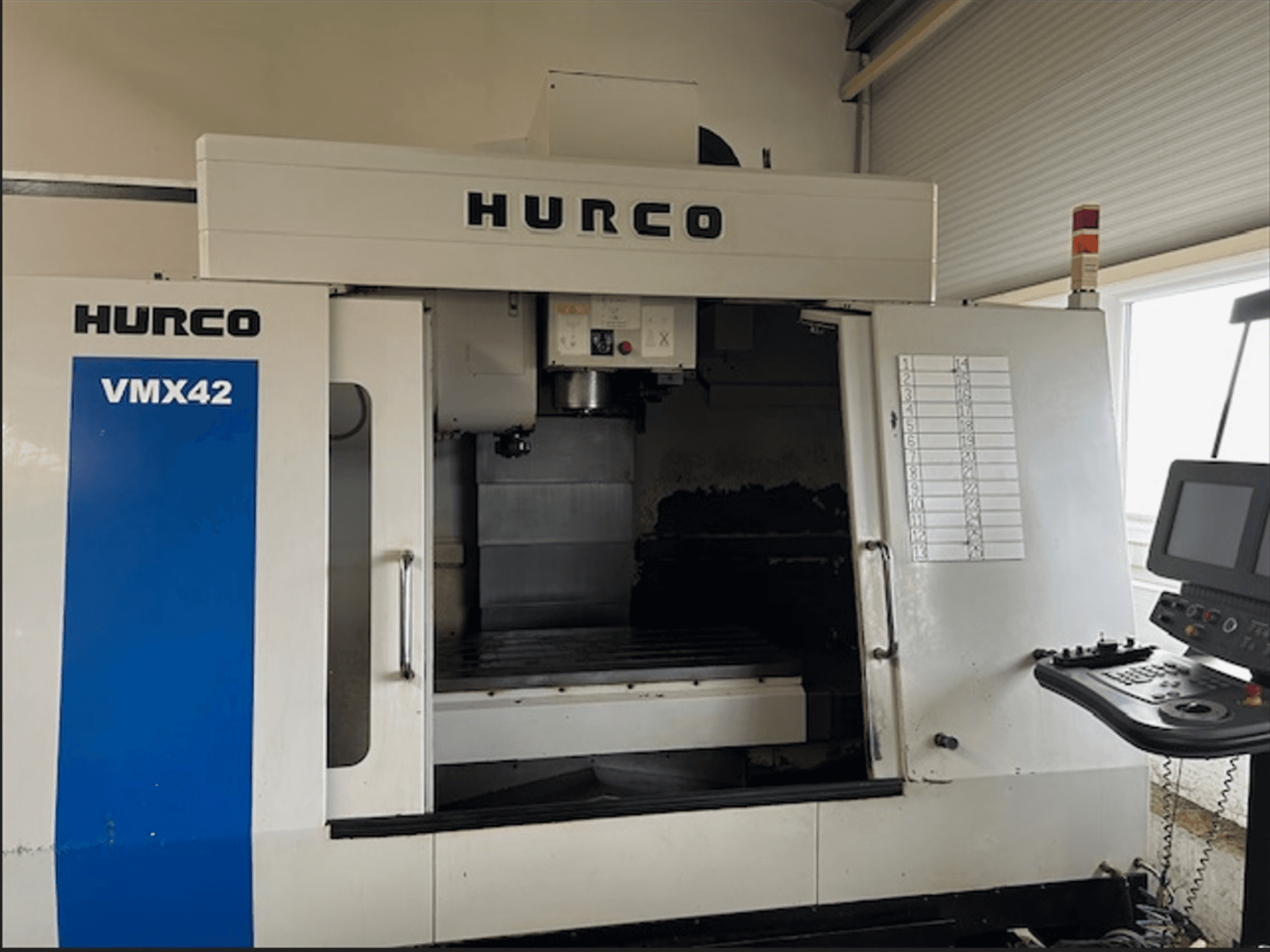 Фрезерный станок с ЧПУ Hurco VMX42, вид спереди, панель управления и открытая рабочая зона для выполнения операций обработки.