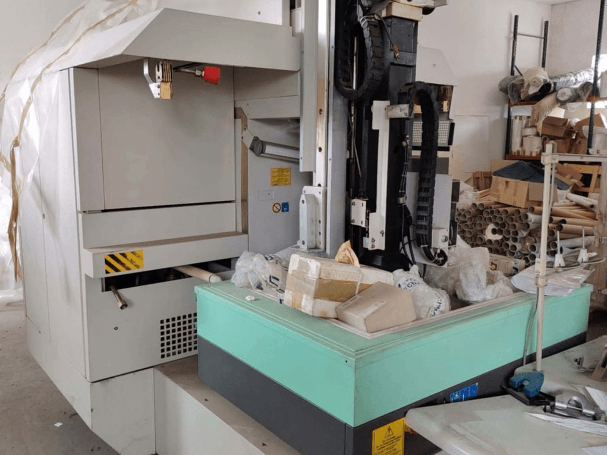 Станок AGIE AGIETRON INTEGRAL 2 для электроэрозионной обработки штамповки, вид спереди, видна панель управления, рабочий стол и окружающий беспорядок.