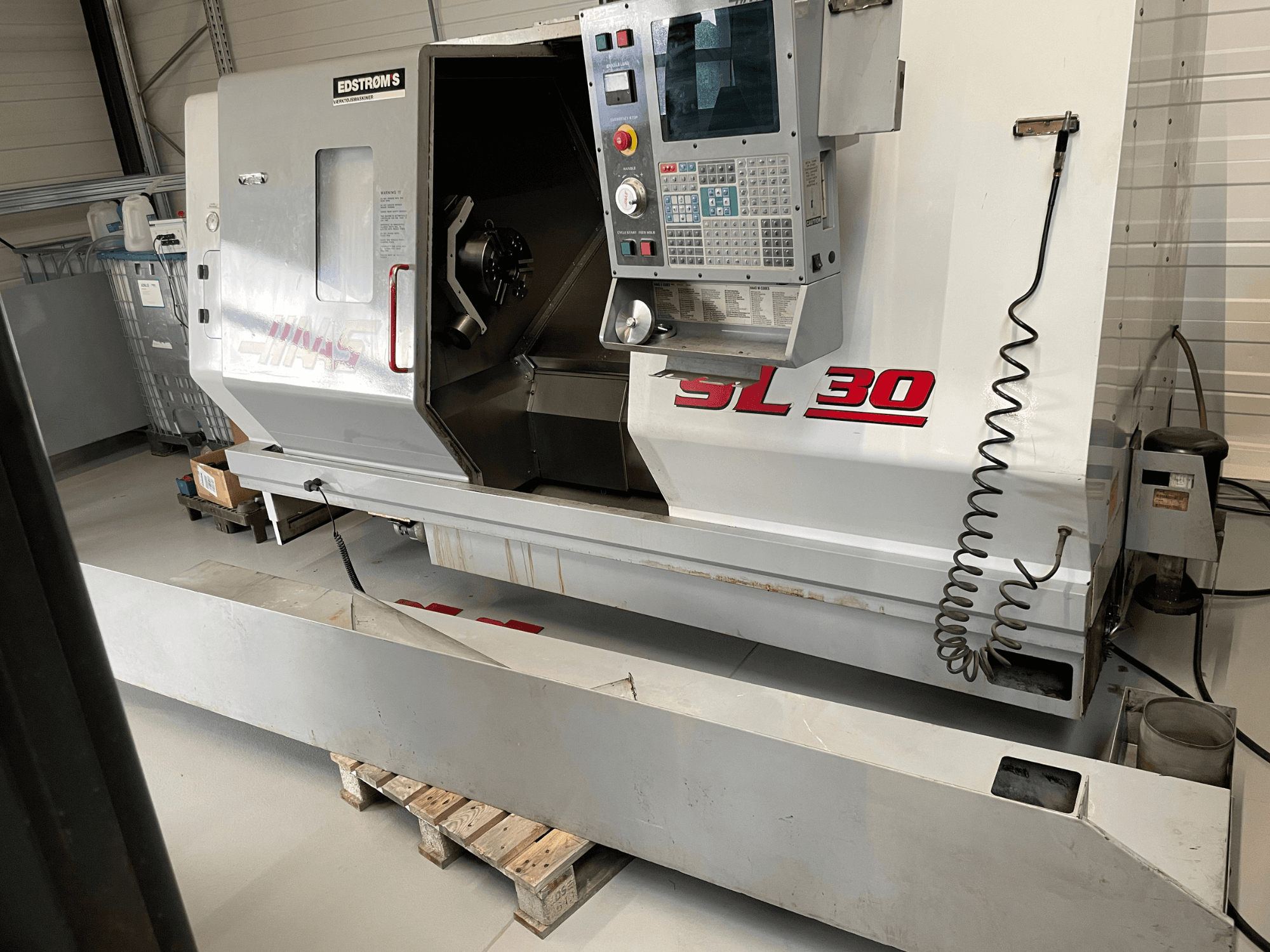 Токарный станок с ЧПУ Haas SL 30 в мастерской, вид сбоку, с панелью управления и открытым шпинделем для выполнения задач по обработке.