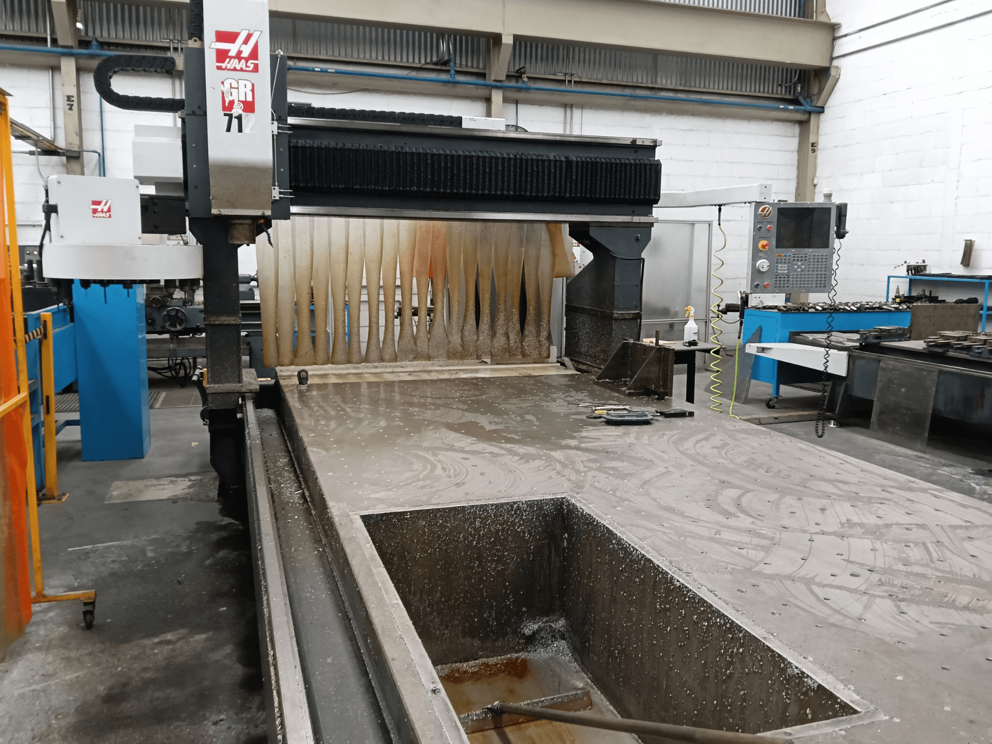 Портальный фрезерный станок HAAS GR-712, вид спереди, на котором видны зона влажной резки и панель управления оператора.