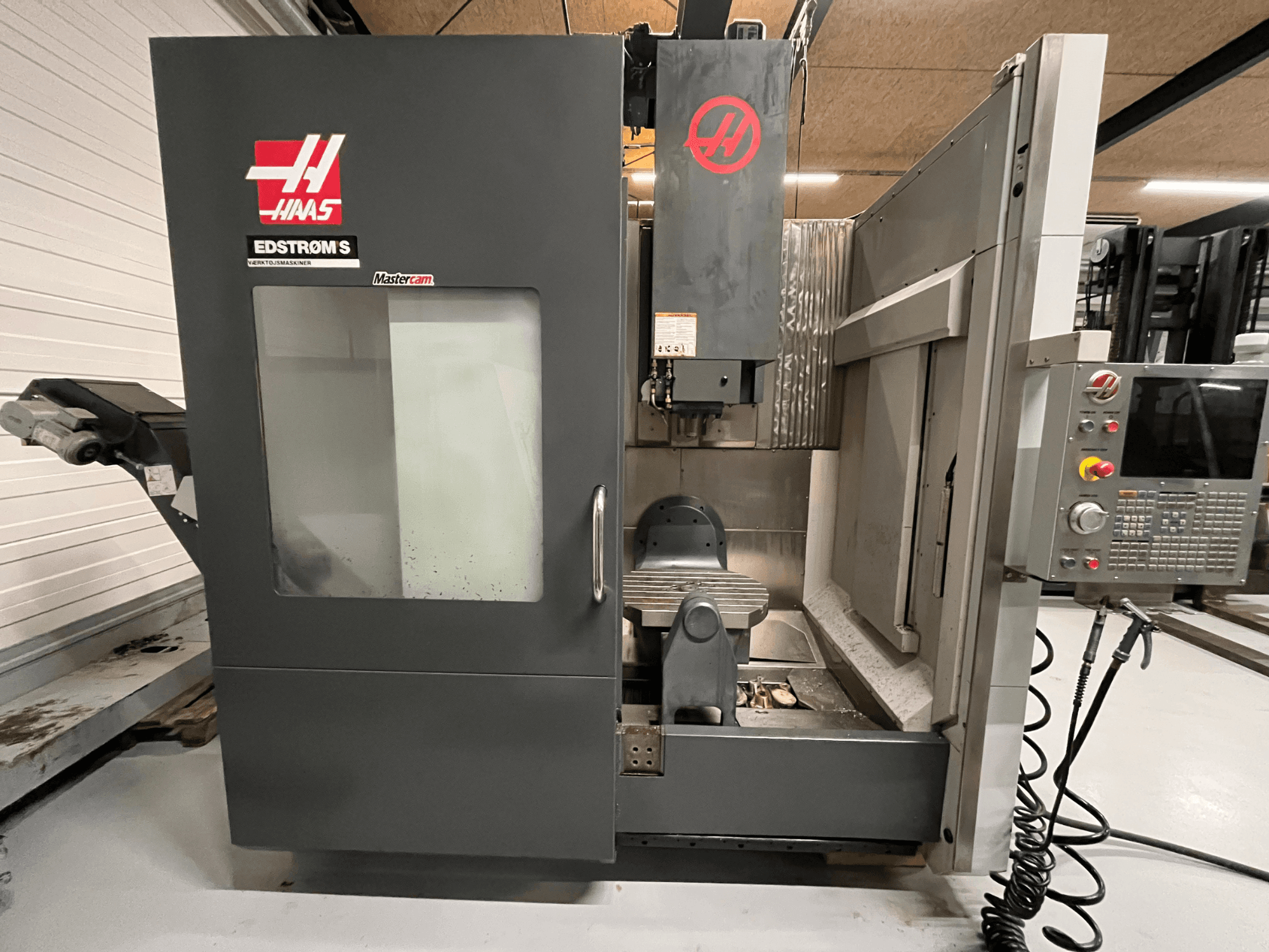 Вид спереди станка с ЧПУ Haas EDSTROM S: панель управления, шпиндельная бабка и стол для обработки.