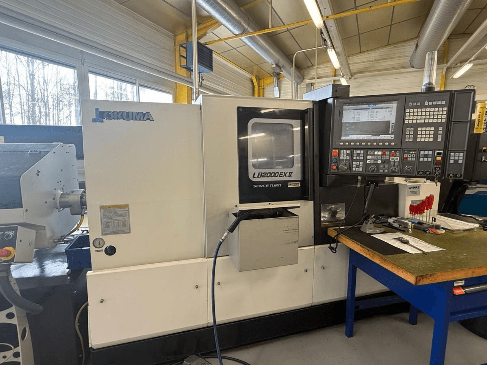 Горизонтальный токарный станок Okuma LB2000EX II, вид спереди; панель управления, зона шпинделя и окружающее рабочее пространство.