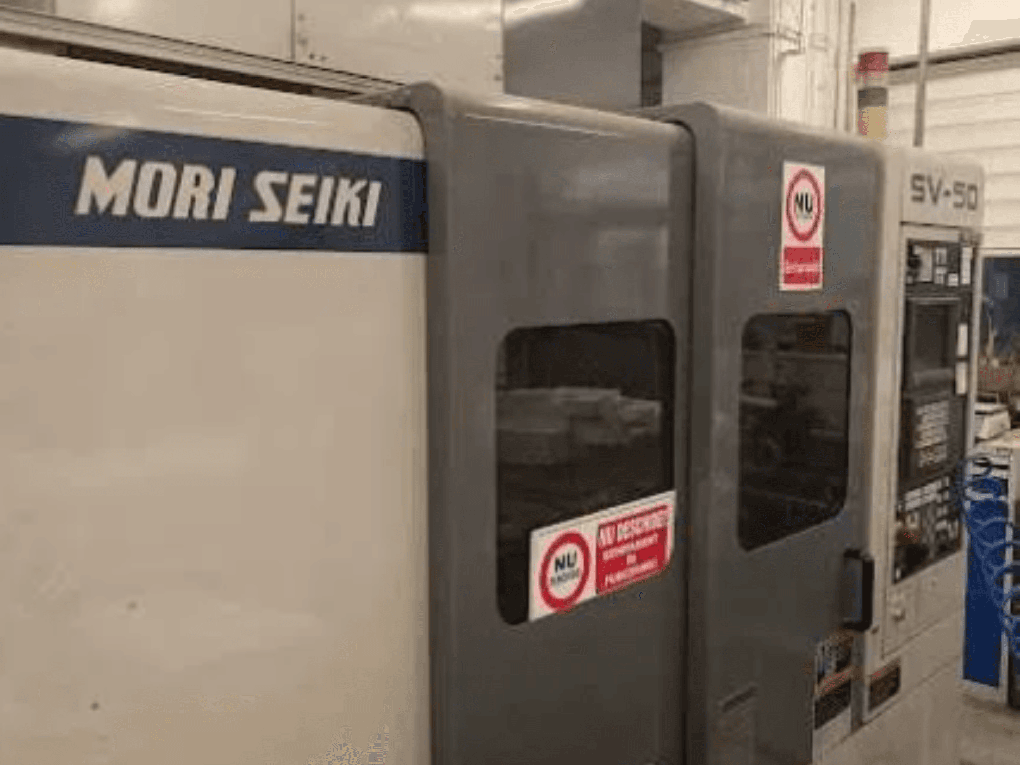 Станок с ЧПУ MORI SEIKI SV-50, вид сбоку; панель управления и предупреждающие наклейки.