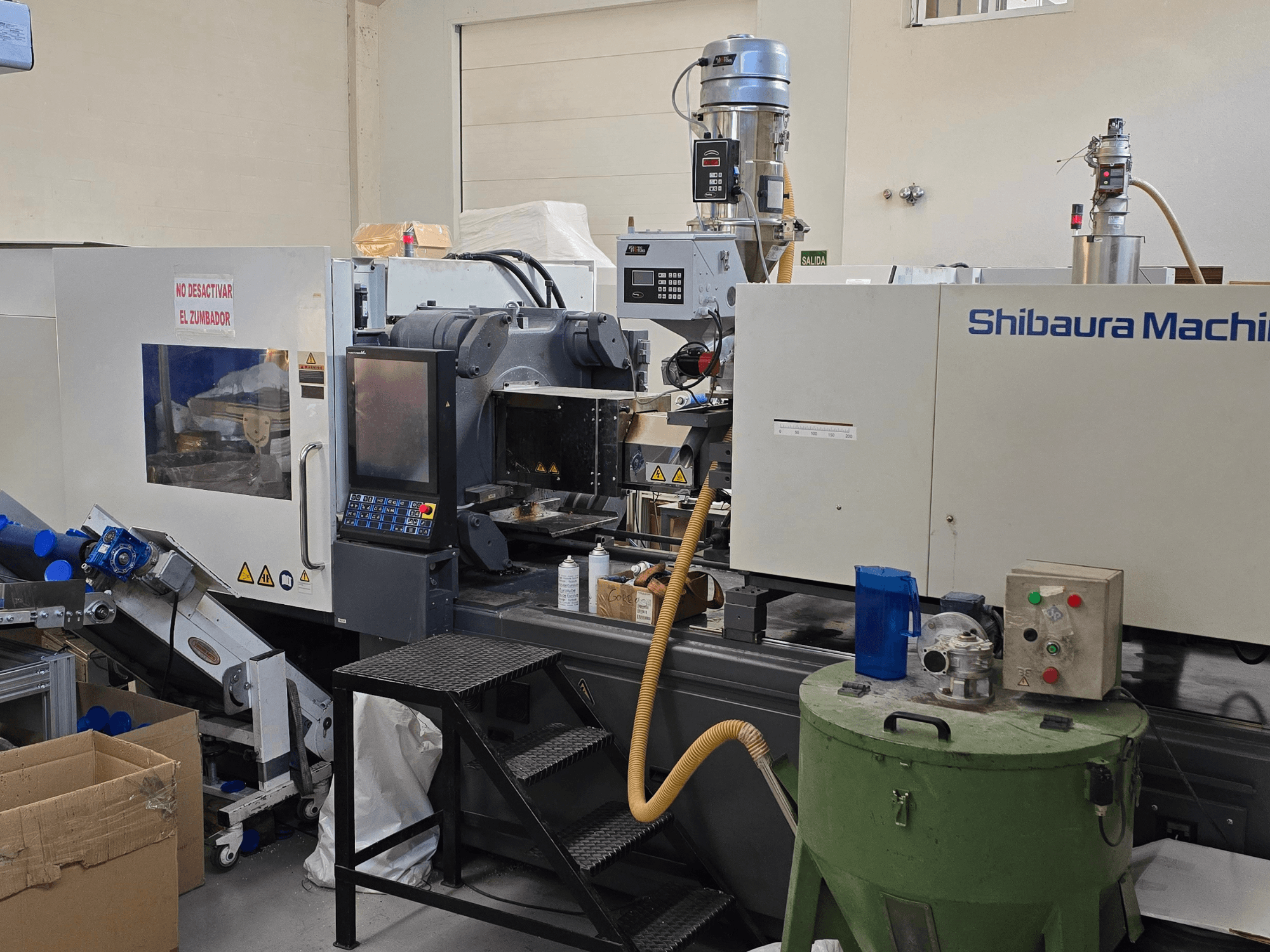 Вид спереди на электрический термопластавтомат SHIBAURA EC230SXIII-8A с панелью управления и соседним оборудованием.