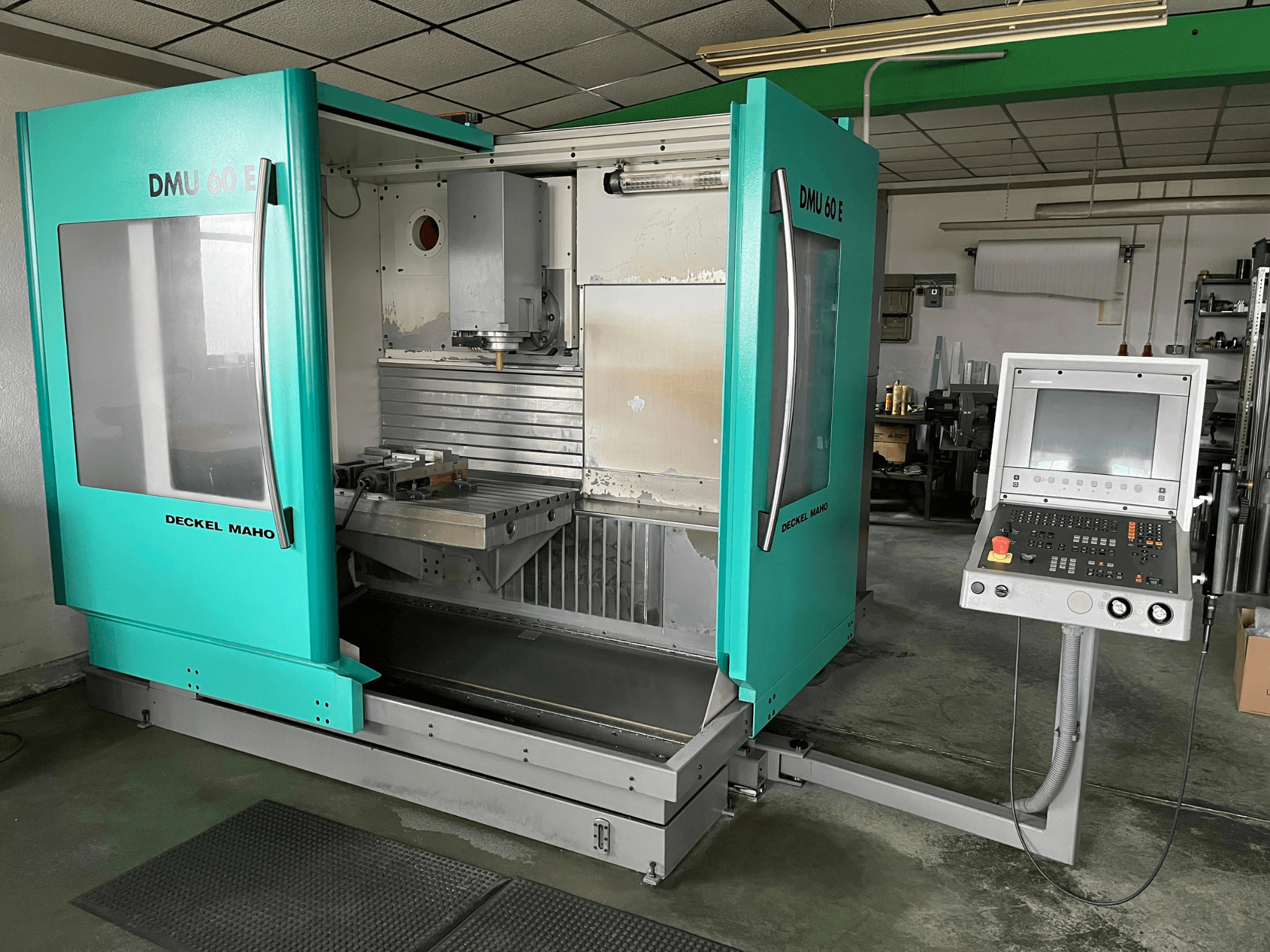 Вертикальный обрабатывающий центр DECKEL DMU 60 E на виде спереди, демонстрирует панель управления и шпиндельную головку для выполнения задач по прецизионной обработке.