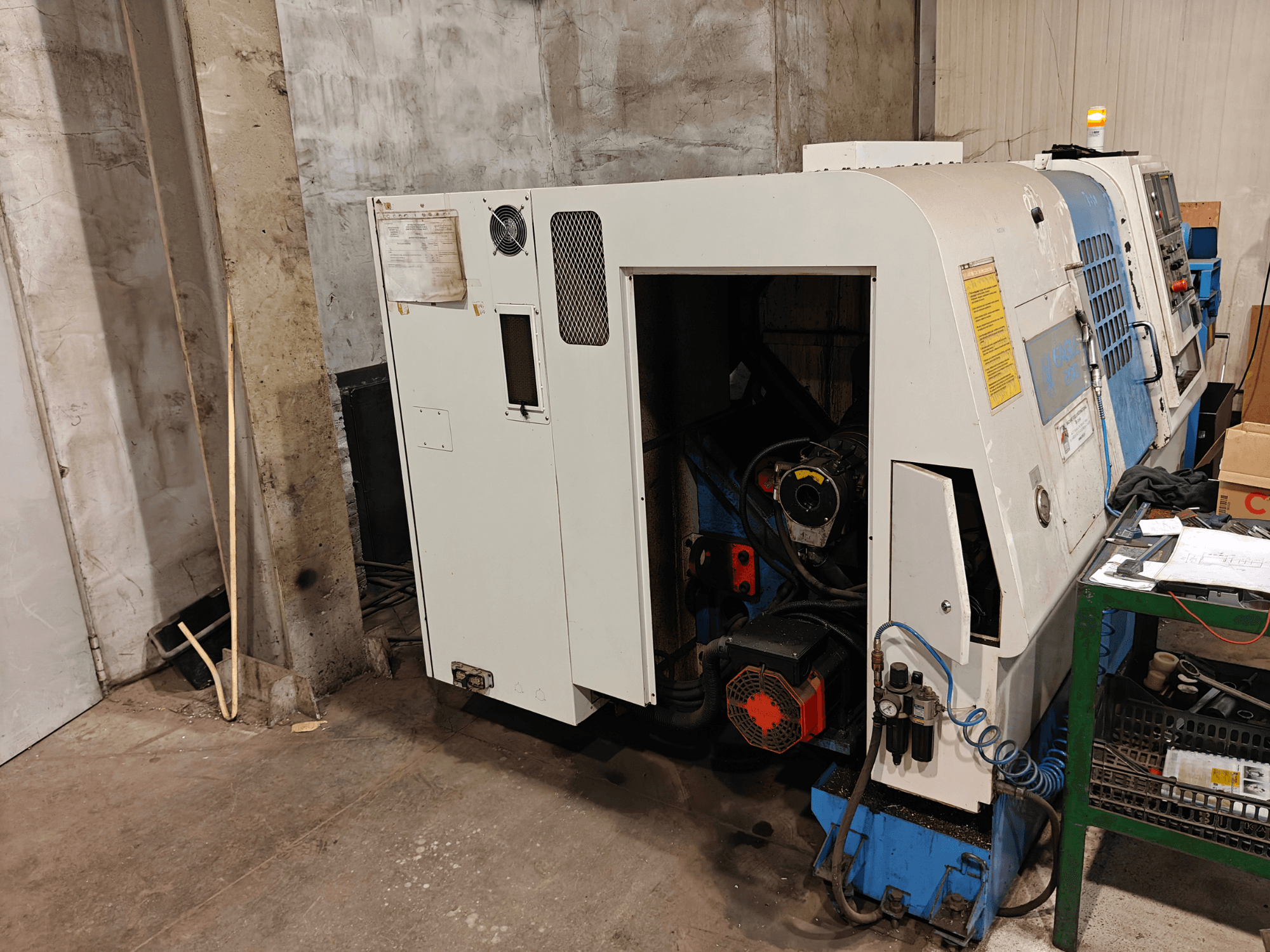 Вид спереди токарного станка, марка и модель не указаны, с элементами управления и видимыми компонентами двигателя.