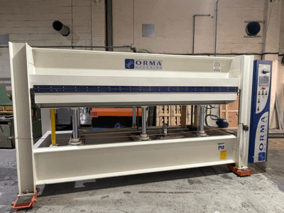 Гидравлический пресс ORMA machinery, вид спереди, с серебристой отделкой, панелью управления справа и вертикальными поршнями для прессования.