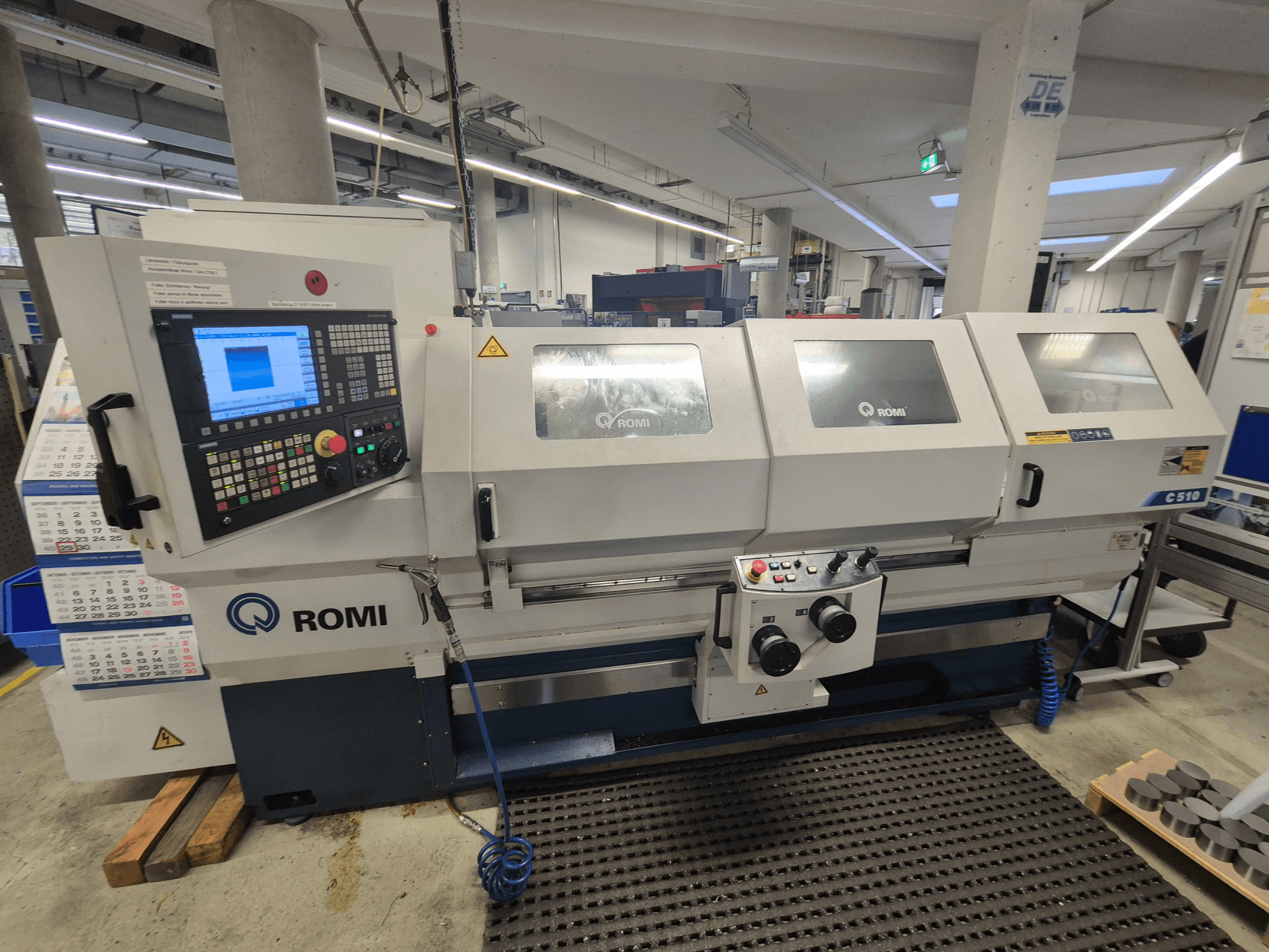 Токарный станок Romi C510 с видом спереди, с цифровой панелью управления и тремя защитными крышками. В комплект входят предупреждающие наклейки.