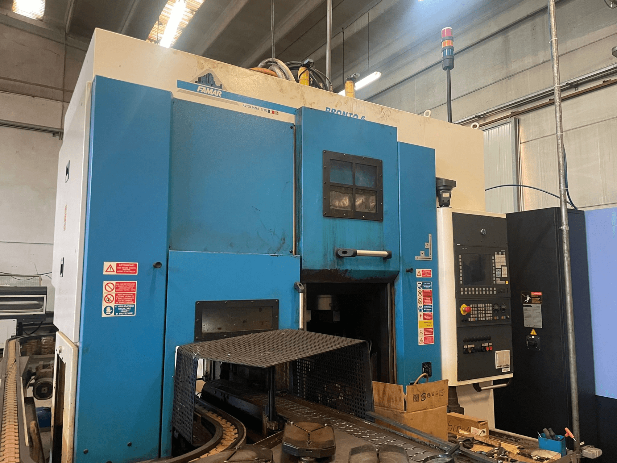 Вертикальный токарный станок Famar Pronto 6 в мастерской, вид сбоку, видна панель управления, рабочие функции и знаки безопасности.