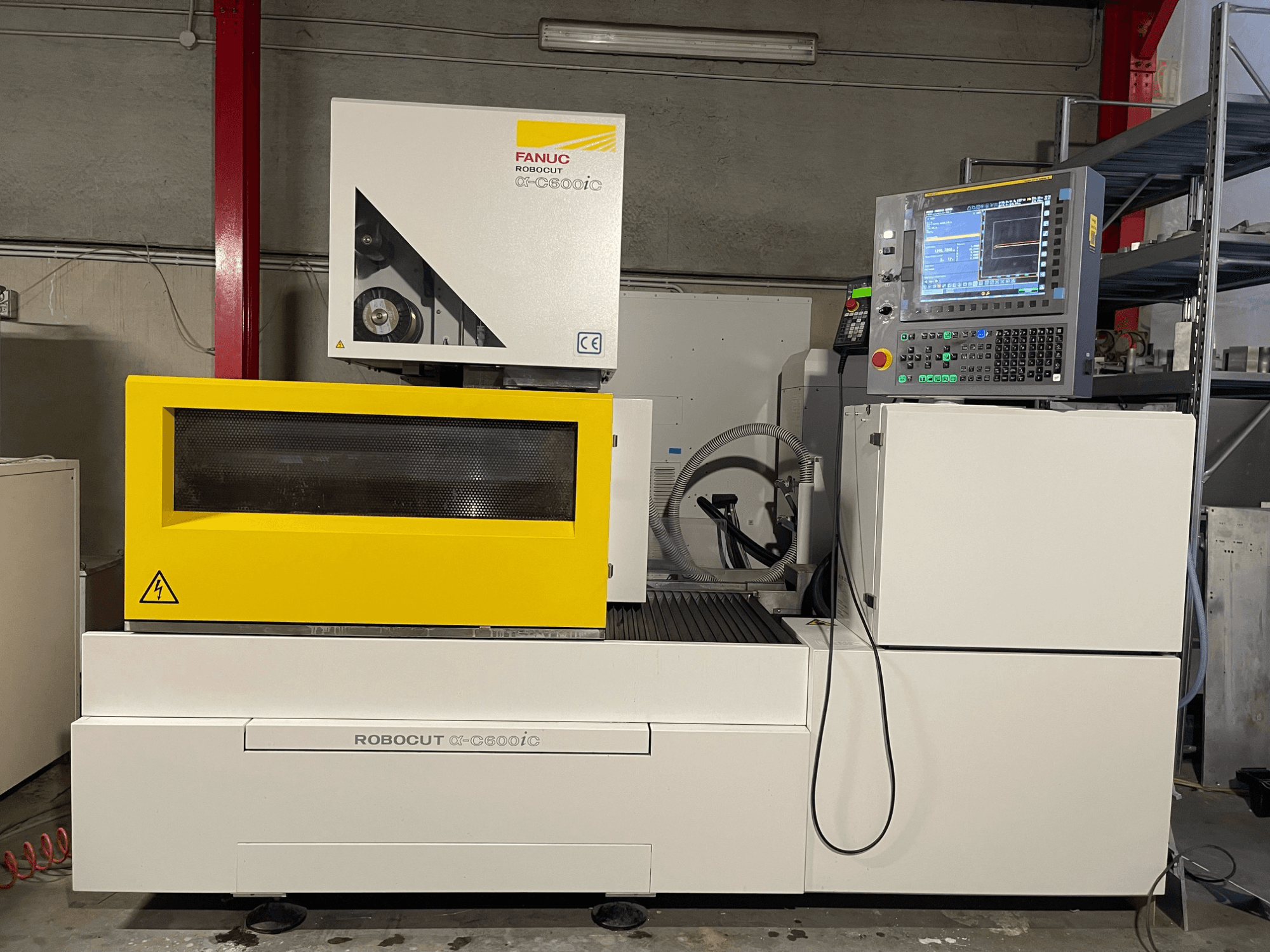 FANUC Robocut α-C600iC, вид сбоку станка с ЧПУ с желтой защитной крышкой и панелью управления, демонстрирующей возможности точной резки.