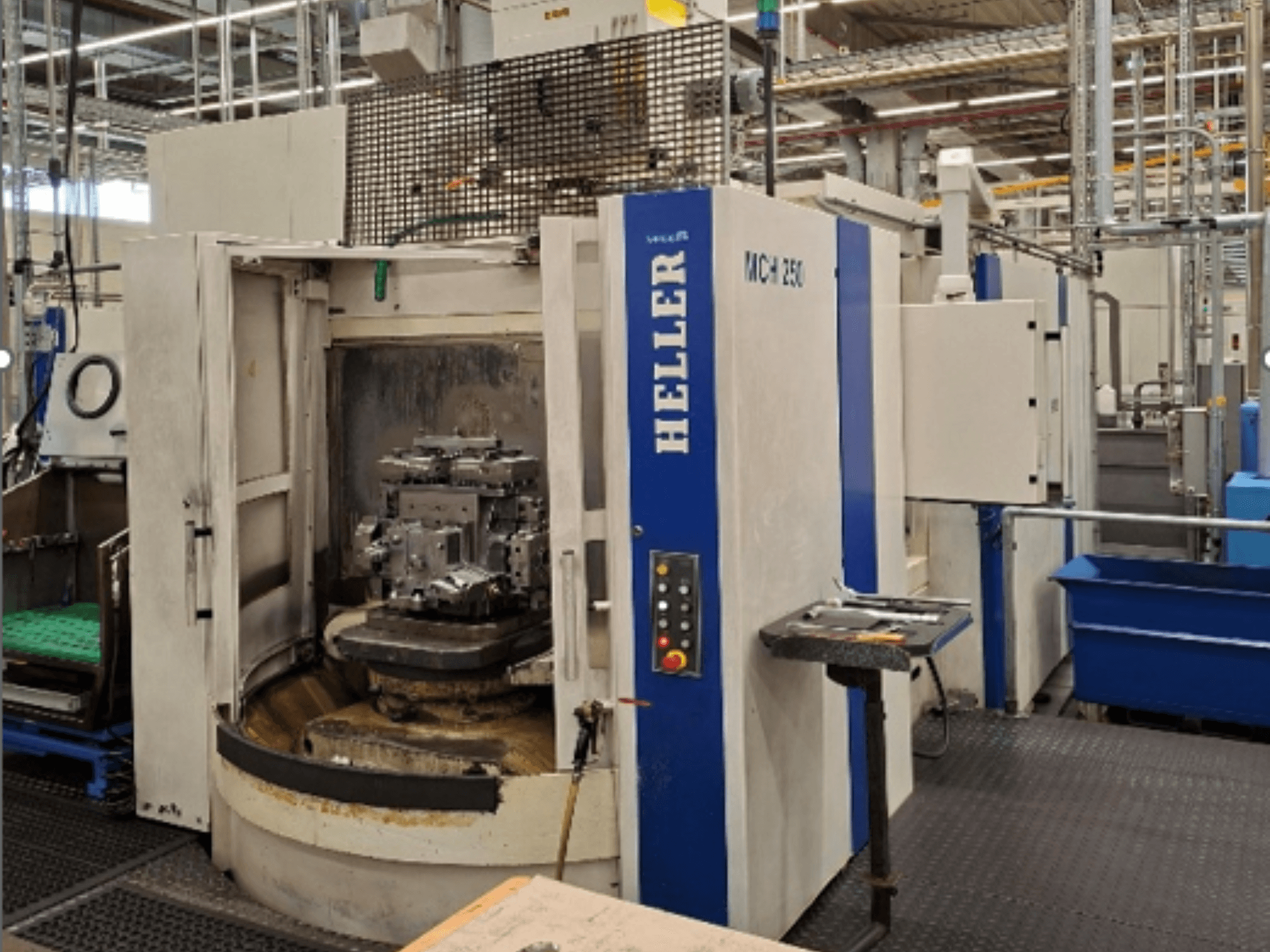 Горизонтальный обрабатывающий центр HELLER MCH 250, вид спереди, с открытыми дверцами, за которыми видна заготовка, на фото видна панель управления.