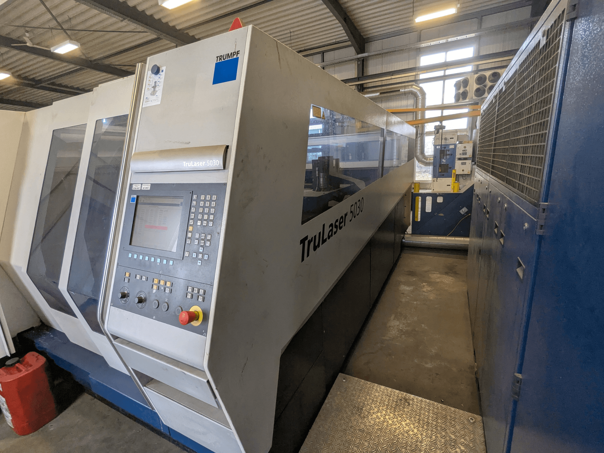 Станок лазерной резки CO2 TRUMPF TruLaser 5030, вид спереди, демонстрирующий панель управления и элегантный дизайн, в промышленной обстановке.