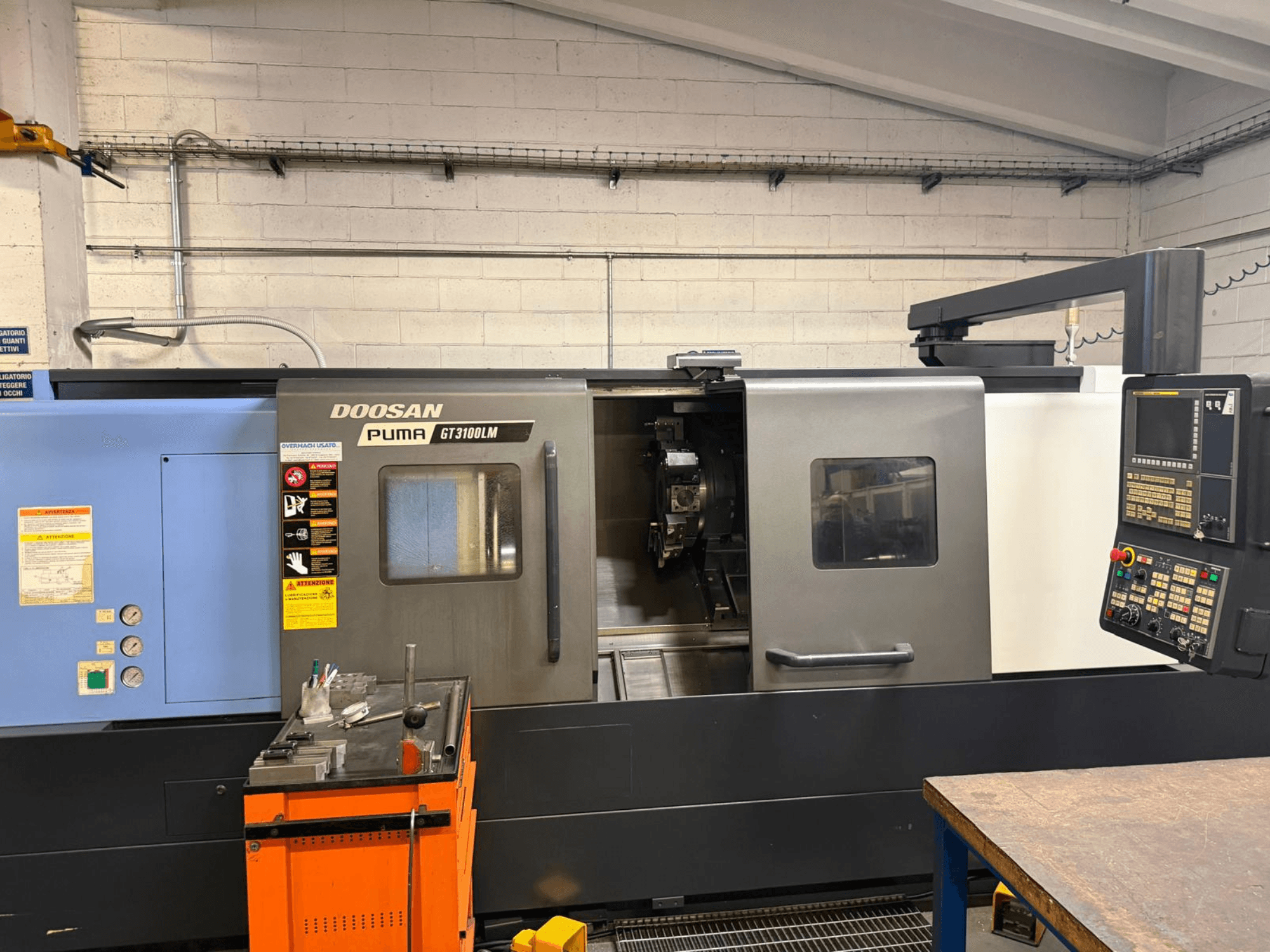 Вид спереди на горизонтальный токарный станок DOOSAN PUMA GT3100LM, демонстрирующий панель управления и рабочую зону с инструментами.