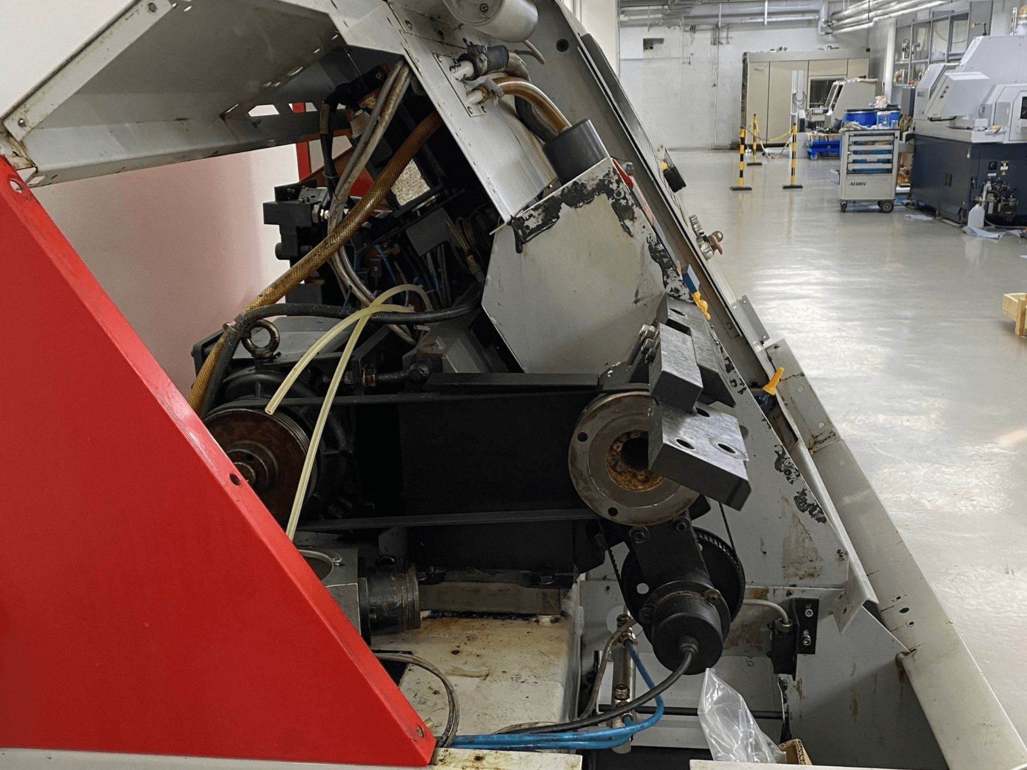 Горизонтальный токарный станок EMCO Emcoturn 325, вид сбоку, демонстрирующий компоненты привода и гидравлики в промышленной обстановке.