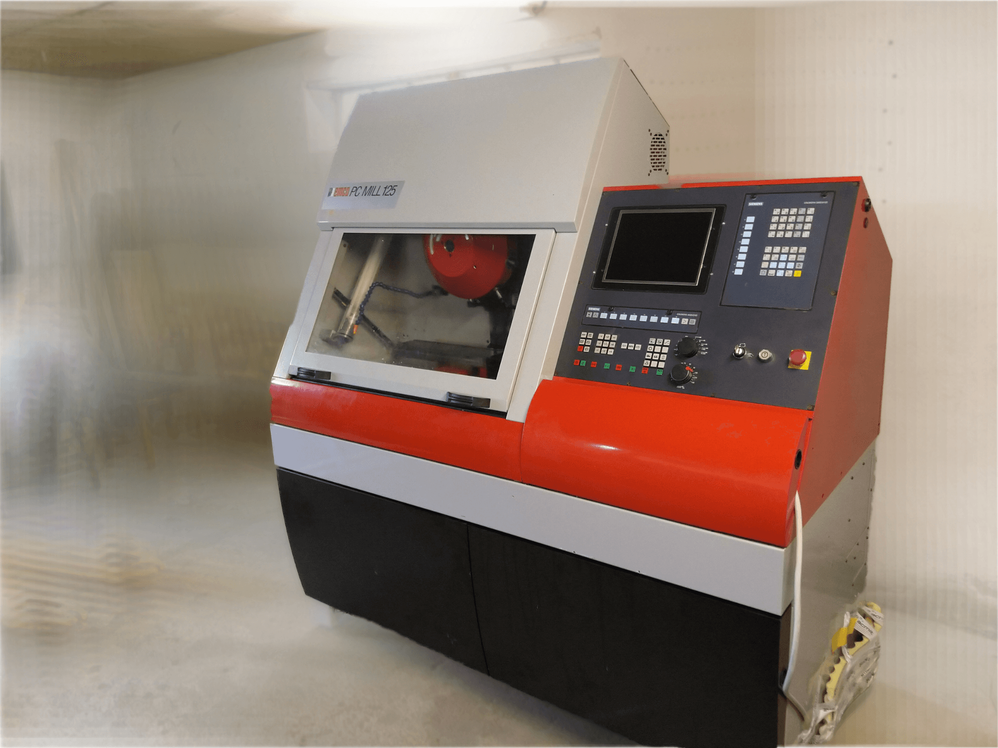 Вертикальный обрабатывающий центр EMCO PC MILL 125, вид спереди с панелью управления и видимой зоной обработки.