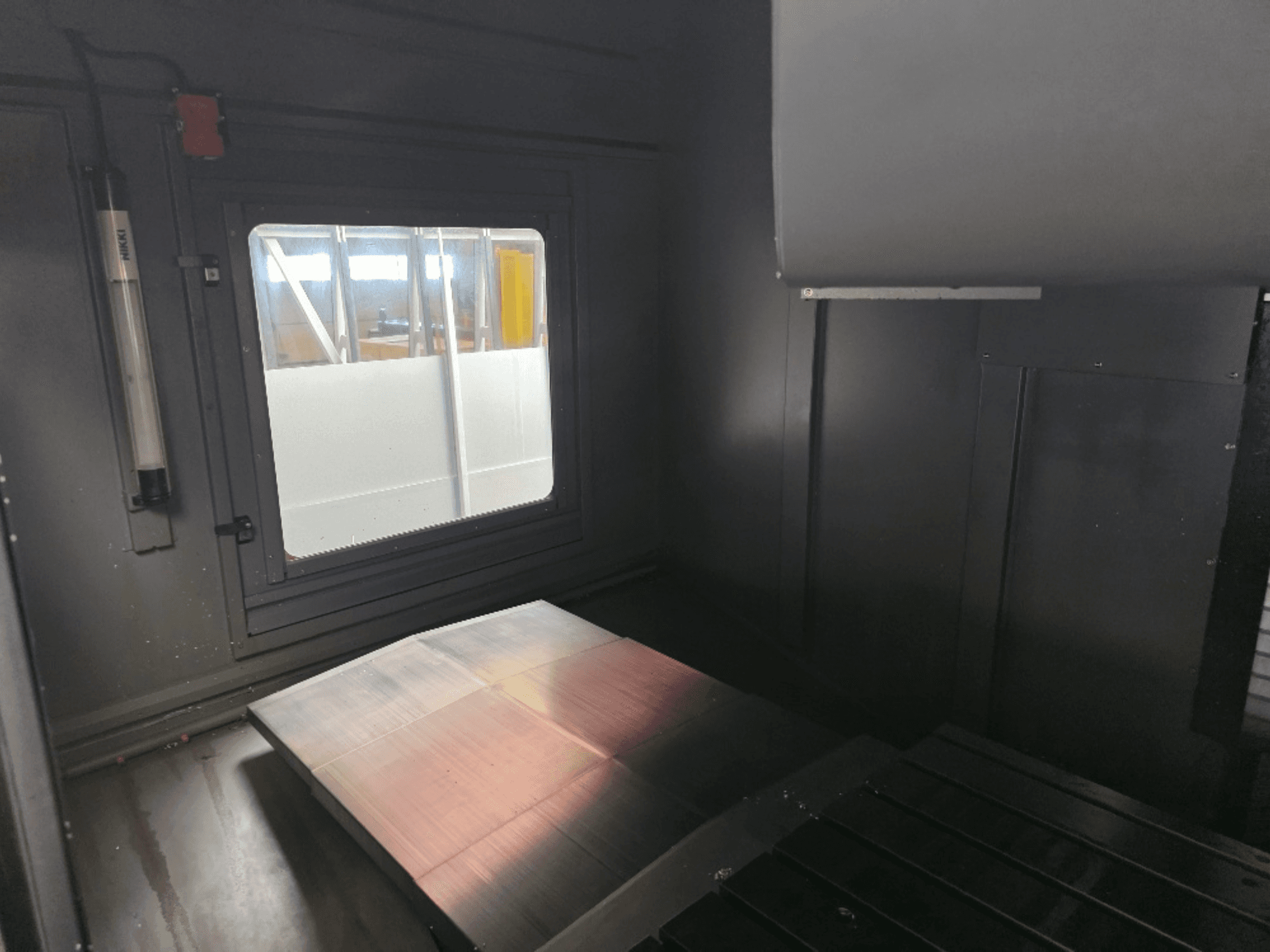 Вид изнутри на корпус машины с полированной металлической пластиной, боковым окном и минимальным освещением. Бренд не виден.