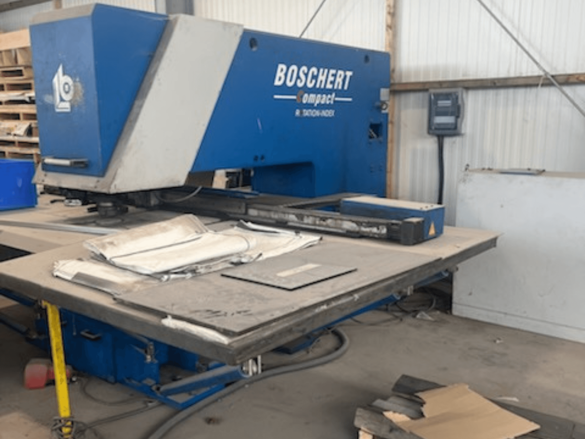 Штамповочный станок с ЧПУ BOSCHERT COMPACT 1000 в цехе; на фотографии показан вид спереди со стальными листами на столе.