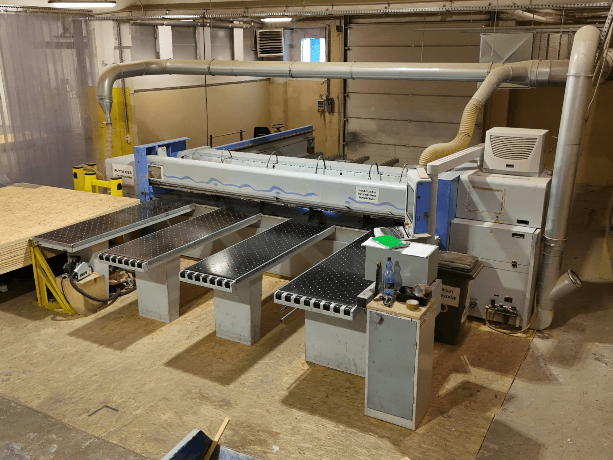 Панельный пильный станок HOLZMA HPP 350/43/38 в цехе, вид сверху, на котором видны зона резания и опорные столы.