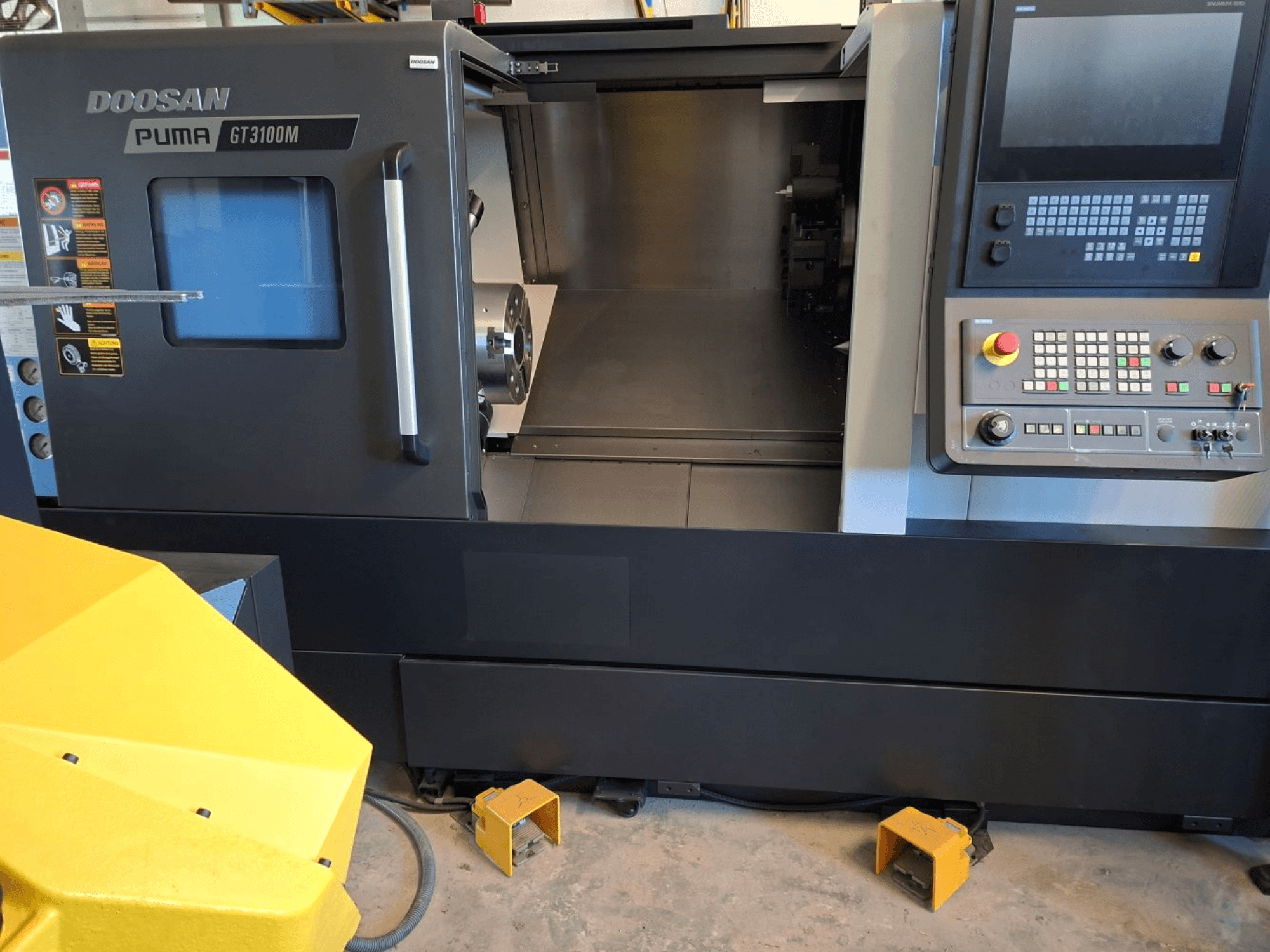Горизонтальный токарный станок DOOSAN Puma GT 3100 M на виде спереди, демонстрирует панель управления, открытую башню и внутреннее рабочее пространство.