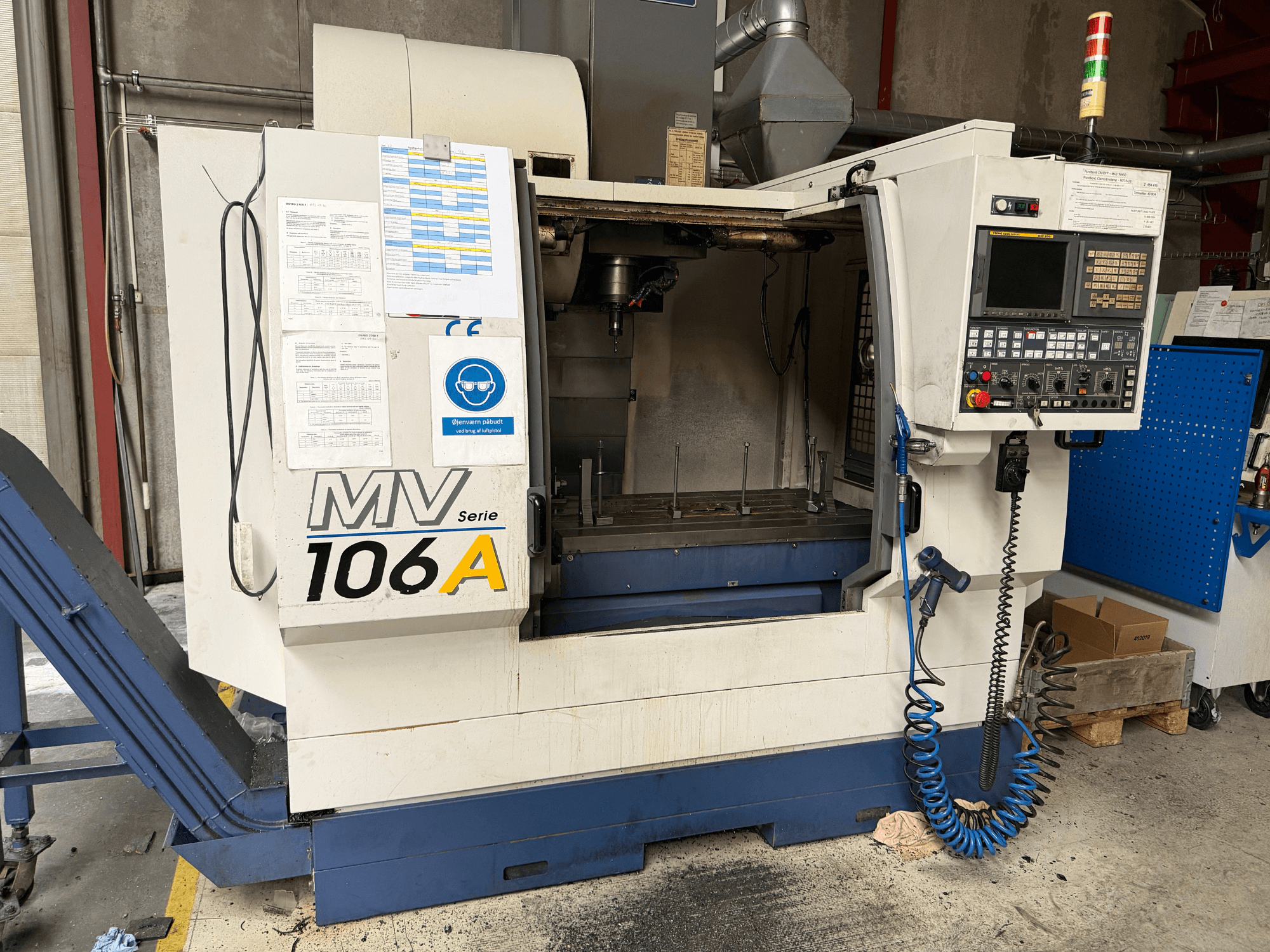 Вертикальный обрабатывающий центр YCM MV106A, вид спереди с панелью управления и рабочей зоной, с прилагаемой технической документацией.