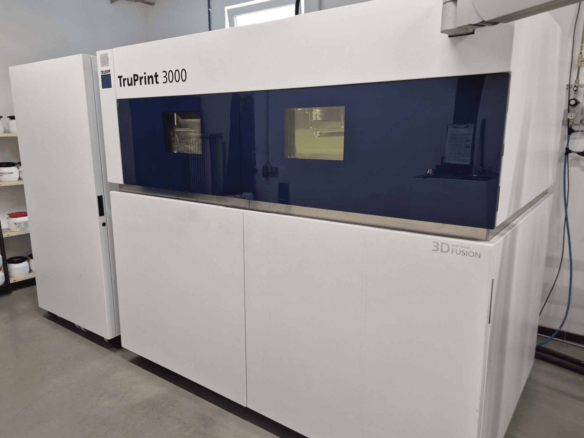 Металлический 3D-принтер TruPrint 3000 с видом спереди, с синей панелью и технологией лазерного сплавления.