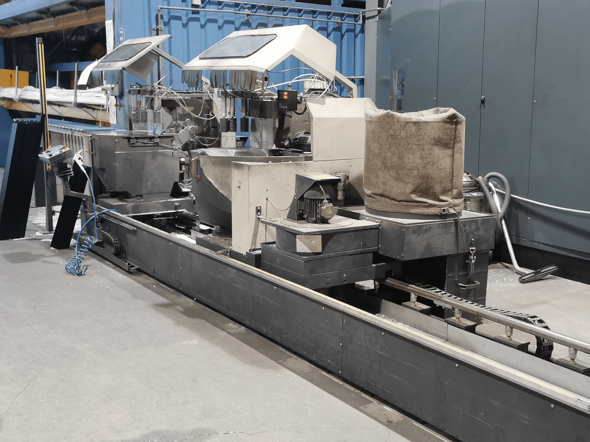 Промышленная машина для переработки, вид сбоку, с бункерами, конвейерной лентой и панелью управления, в заводских условиях.