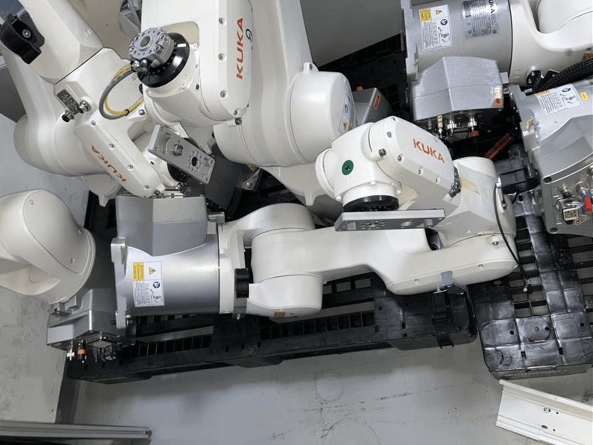 Рука робота KUKA KR 6 R900 CR в виде сверху, с множеством шарниров и моторов, на черном основании с кабелями.