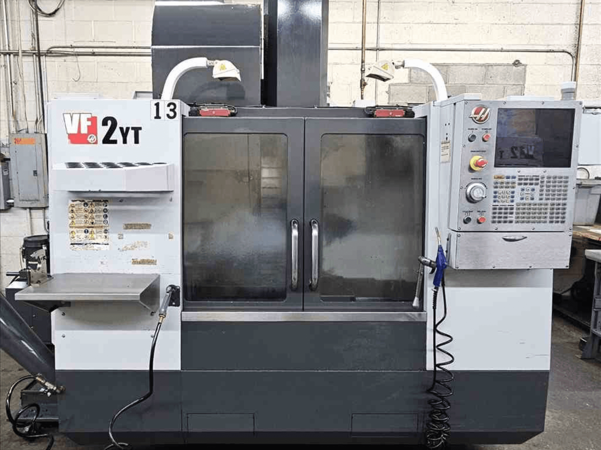Вид спереди вертикального обрабатывающего центра HAAS VF-2YT, панель управления и стеклянные двери.