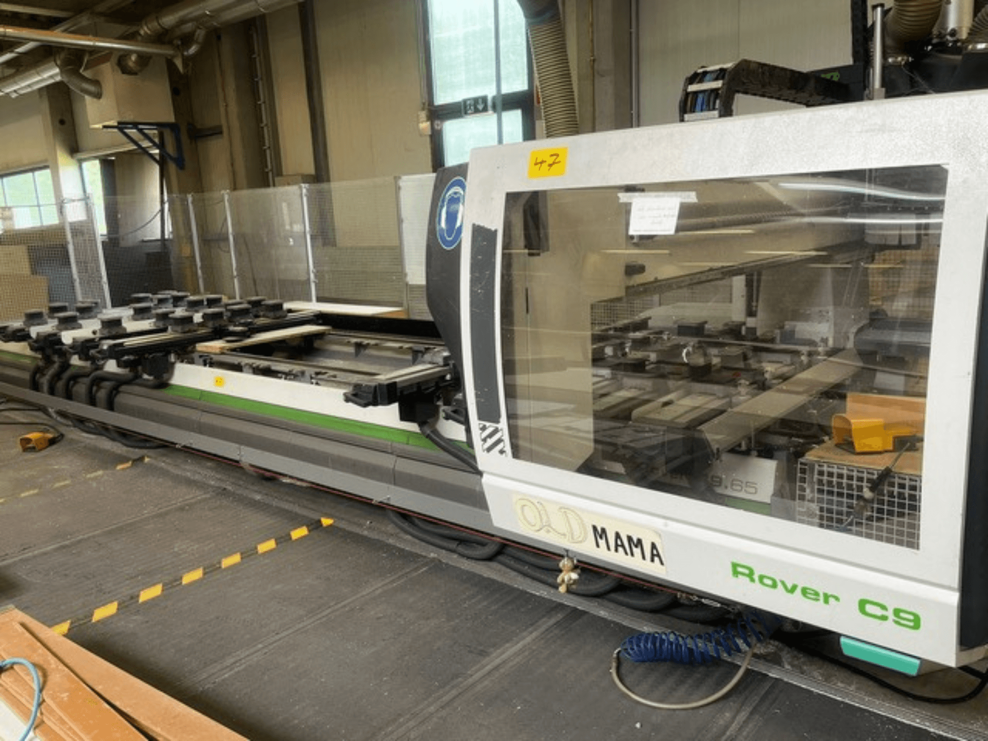 Фрезерный станок с ЧПУ BIESSE Rover C 9.65 в мастерской, вид сбоку на панель управления и рабочий стол с зажимами.