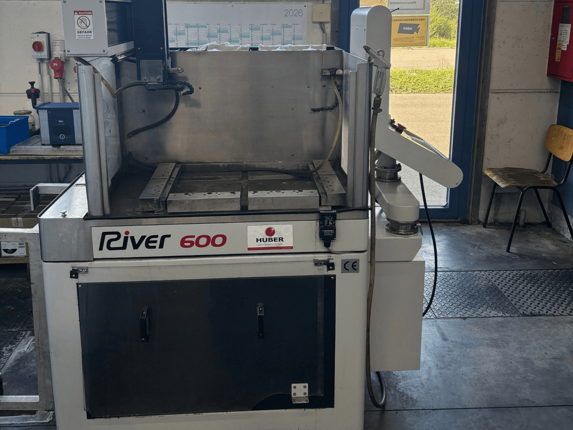 Машина для электроэрозионной обработки по глубинной вырубке HUBER River 600 с ЧПУ, вид спереди, с частично открытой рабочей камерой и панелью управления.