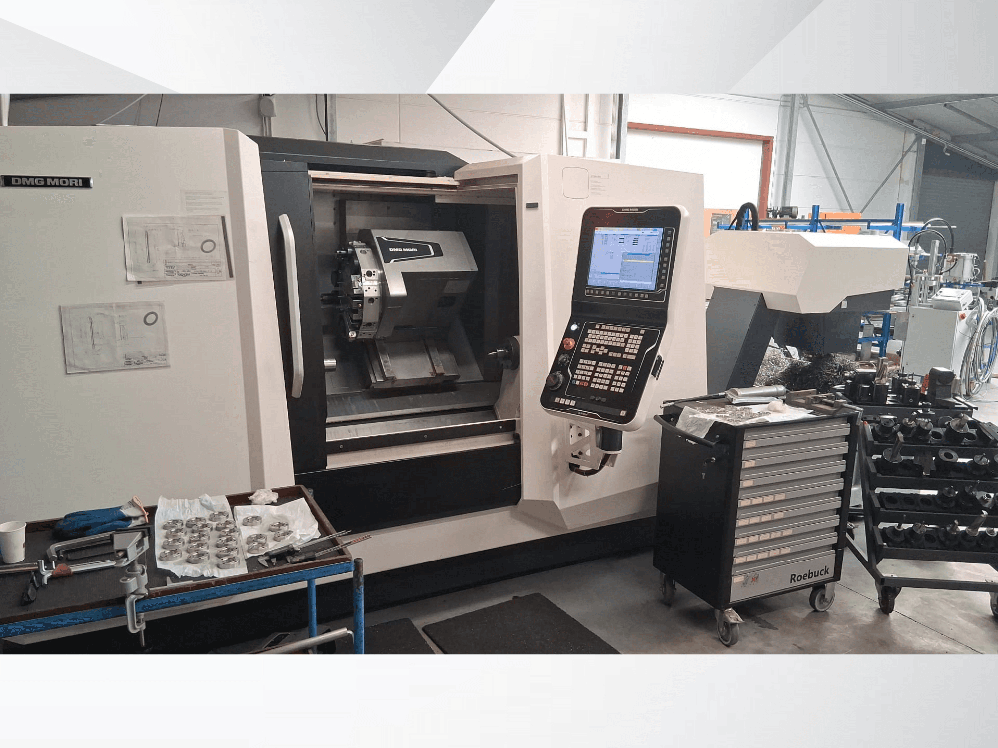 Горизонтальный токарный станок DMG MORI CLX450 с видом спереди: панель управления, рабочая зона, инструменты и металлические детали.
