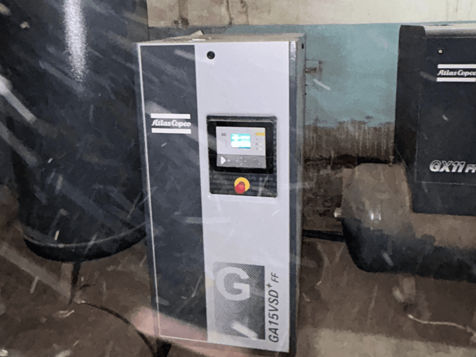 Воздушный компрессор Atlas Copco GA15VSD+FF, вид спереди, с панелью управления, оснащенной дисплеем и красной кнопкой аварийной остановки.