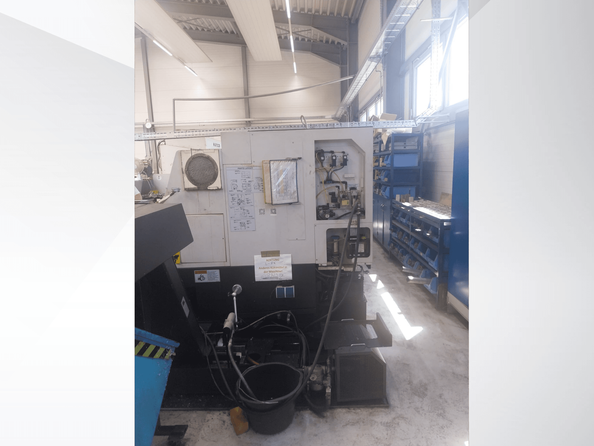 Mazak QUICK TURN NEXUS 200 MS, вид сбоку, на котором видны панель управления, шланги и зона размещения инструментов в условиях цеха.