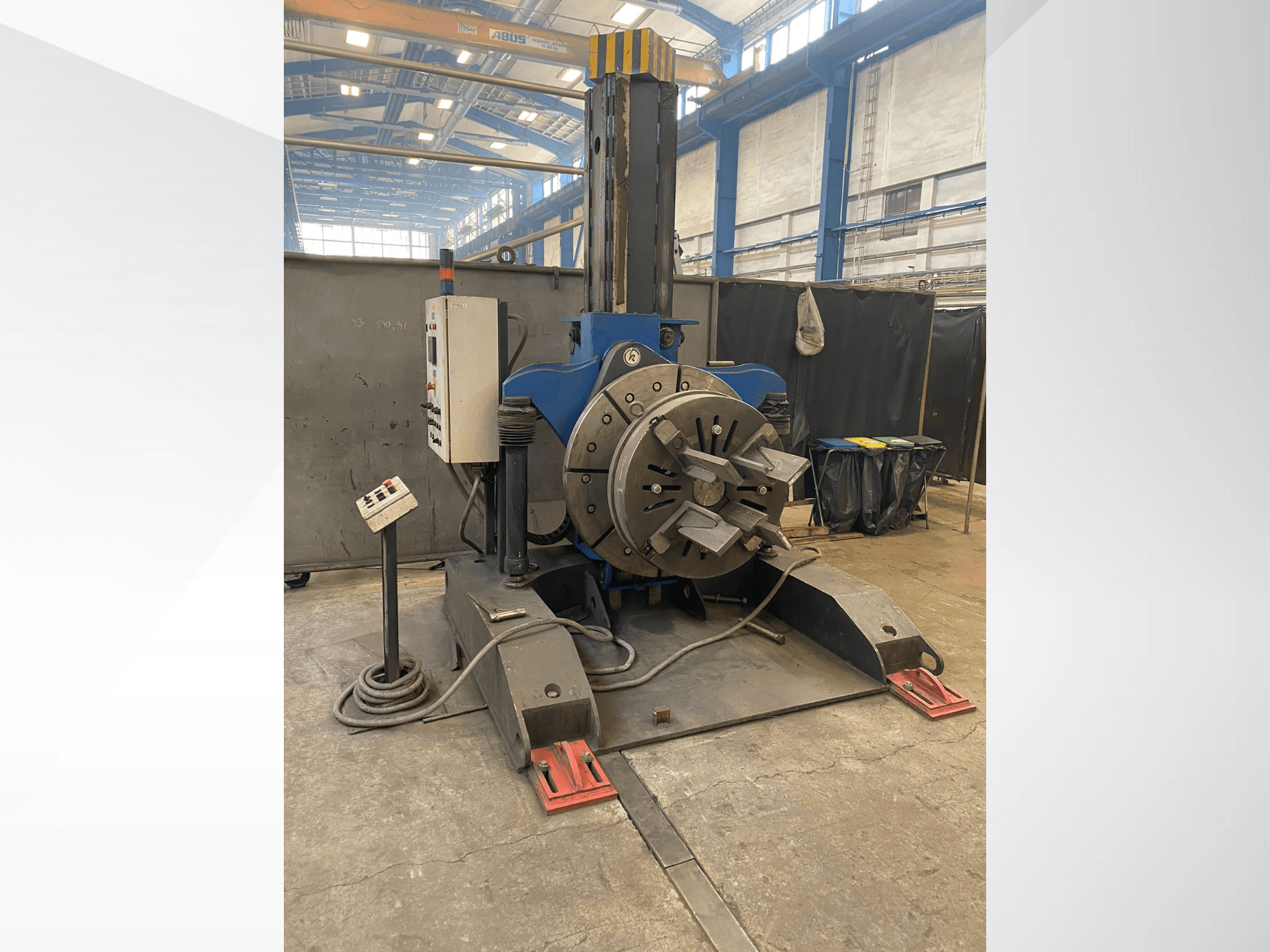 Синий промышленный токарный станок с круглой вращающейся головкой и панелью управления, вид сбоку, в мастерской.