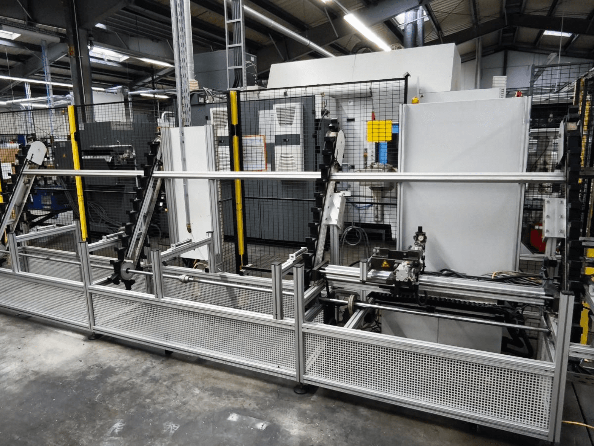 Система обработки заготовок LOHMEIER Schräglademagazin на переднем плане, демонстрирует металлическую конструкцию и встроенные механические компоненты.