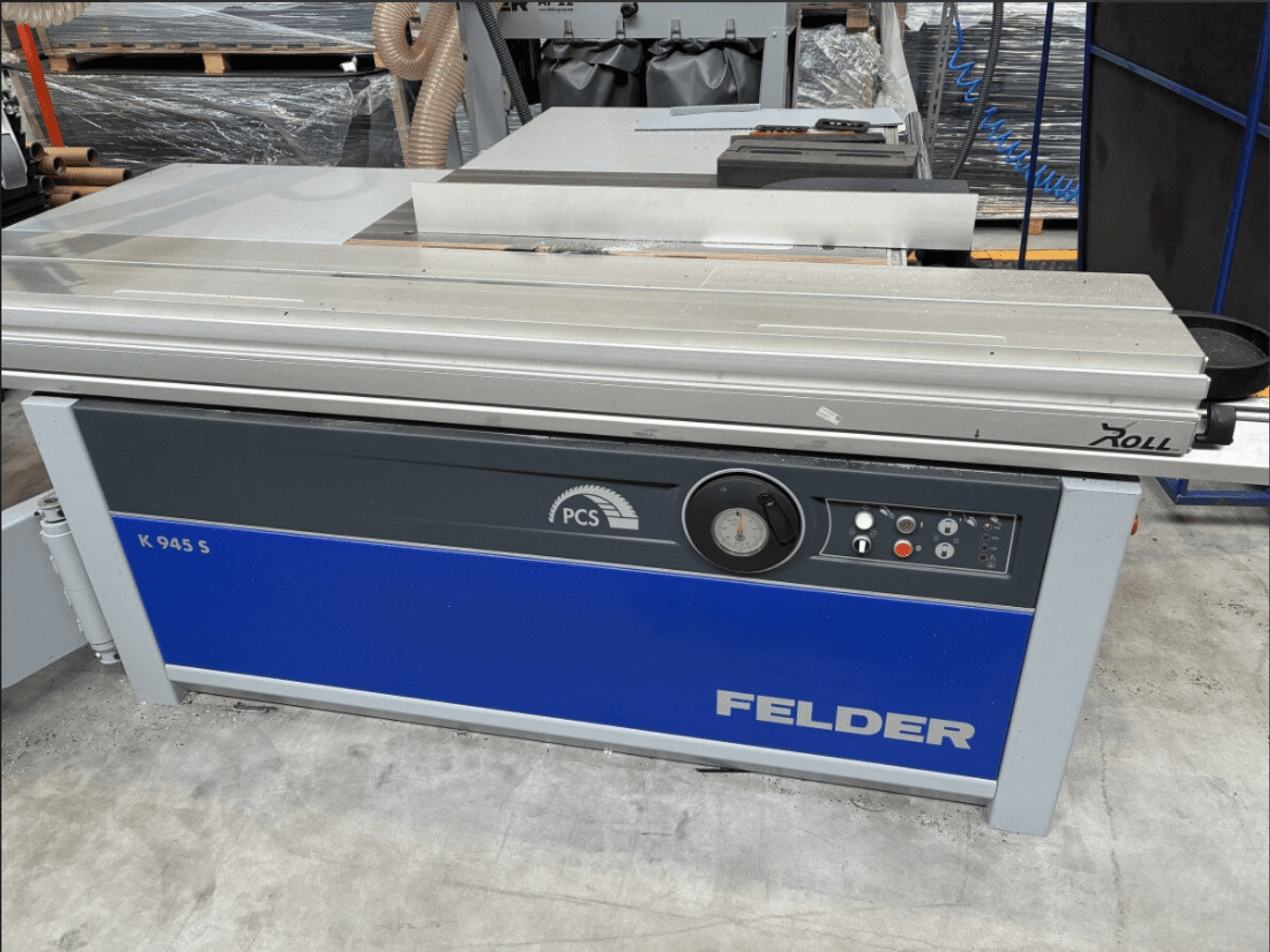 Пила для распиловки плит FELDER K 945 S, вид спереди с панелью управления, столом и средствами безопасности, установленная на полу мастерской.
