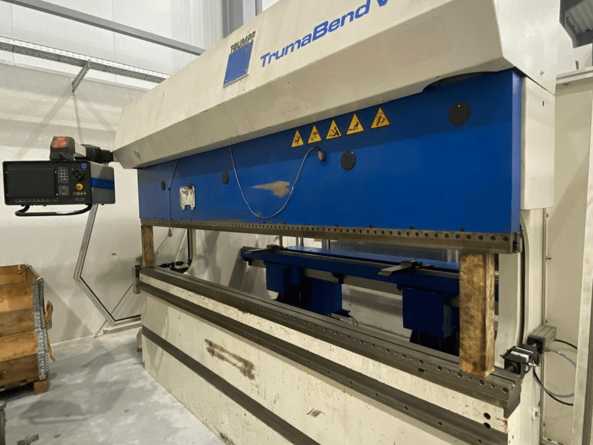 Гибочный пресс TRUMPF Trumabend V130, вид спереди, с панелью управления, синими элементами и видимыми предупреждающими надписями о безопасности.