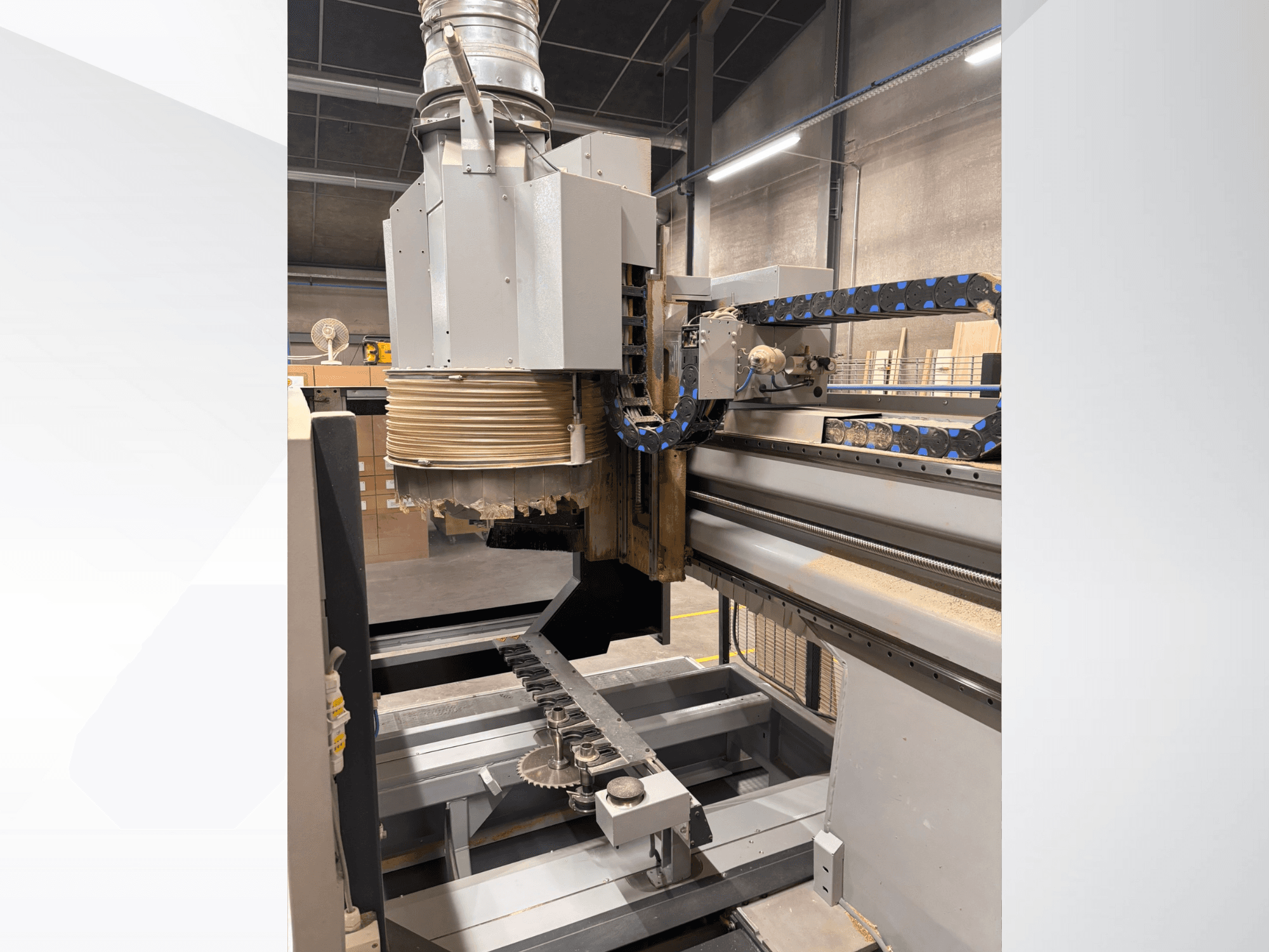 Фрезерный станок с ЧПУ с большим шпинделем и конвейером, вид сбоку, демонстрирующий дереворежущие инструменты и компоненты оборудования.