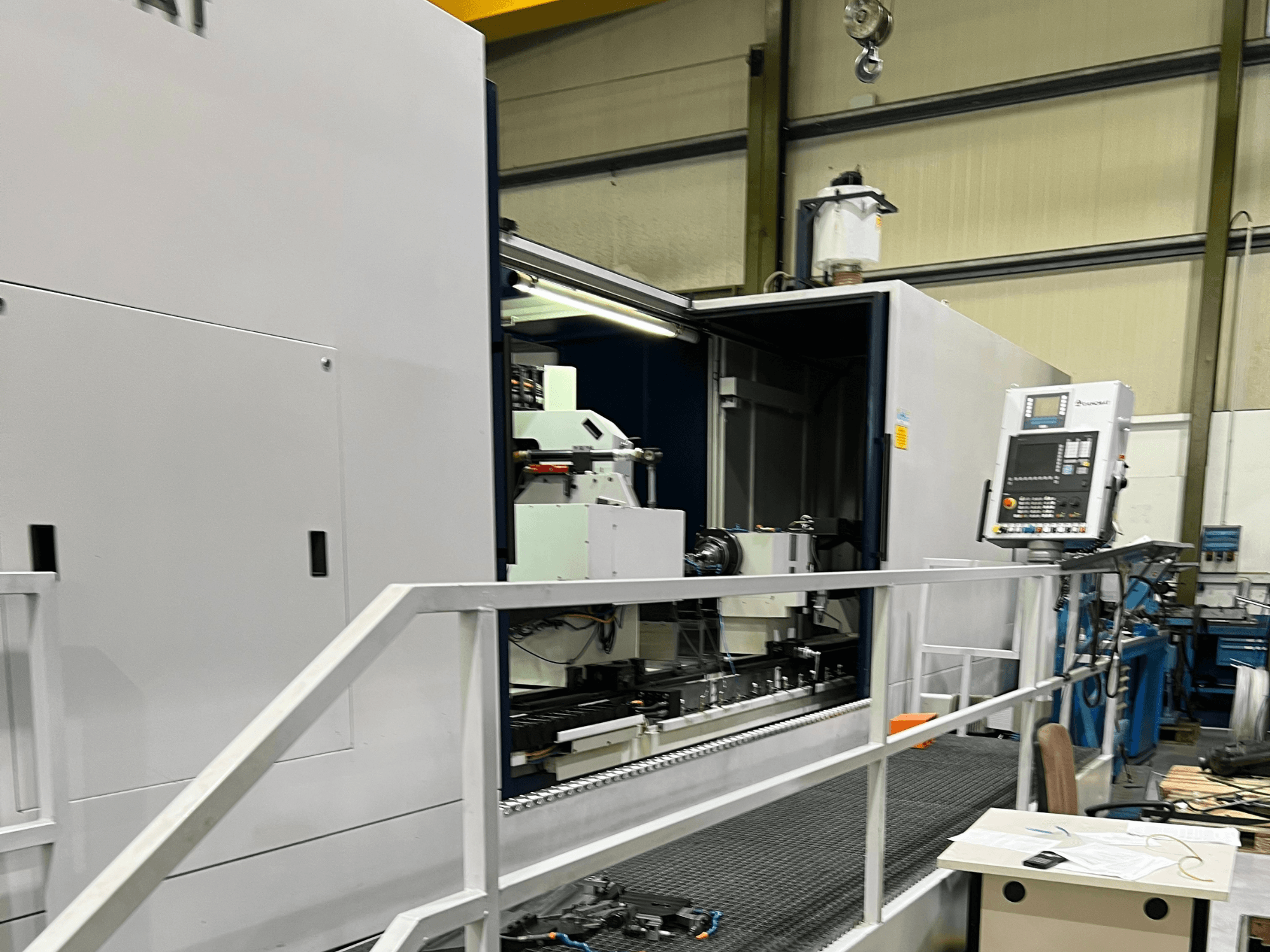 Обрабатывающий центр с ЧПУ с открытым боковым видом, демонстрирующим органы управления, держатель инструмента и основные компоненты внутри. Детали бренда не видны.