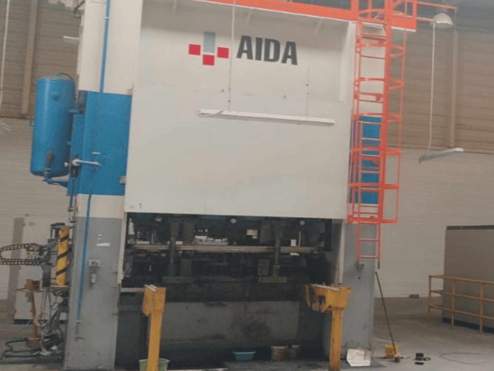 Механический штамповочный пресс AIDA 315/2MR/LD/TE3, вид спереди, демонстрирует гидравлические компоненты и лестницу безопасности.
