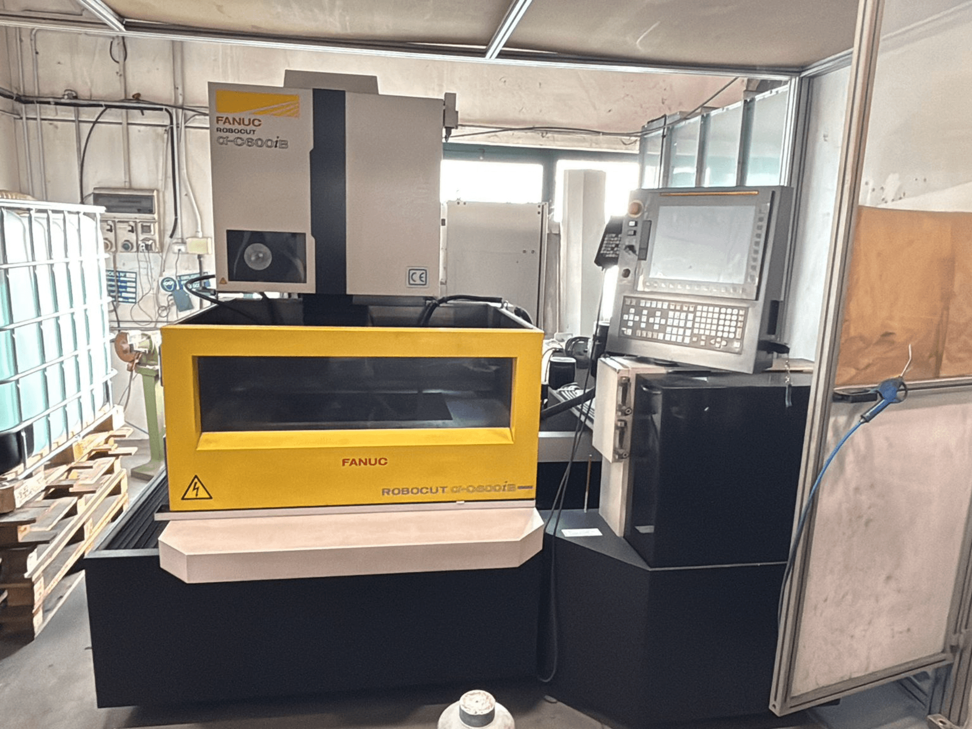 Вид спереди на станок с ЧПУ FANUC Robocut α-0iE в желтом корпусе, на котором видны панель управления и дисплей.